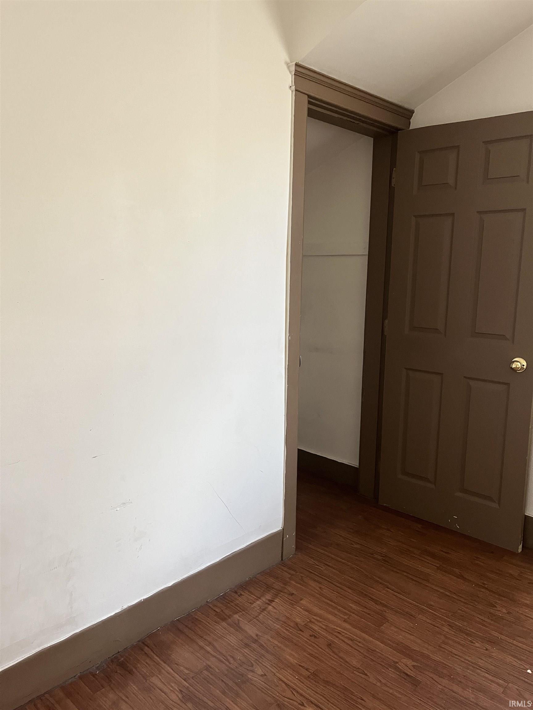 Corridor featuring dark wood finished floors and vaulted ceiling