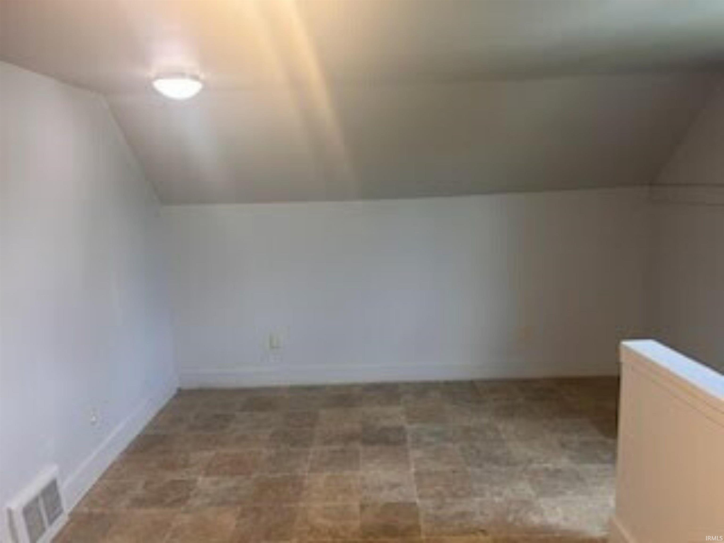 Bonus room featuring vaulted ceiling and stone finish floors
