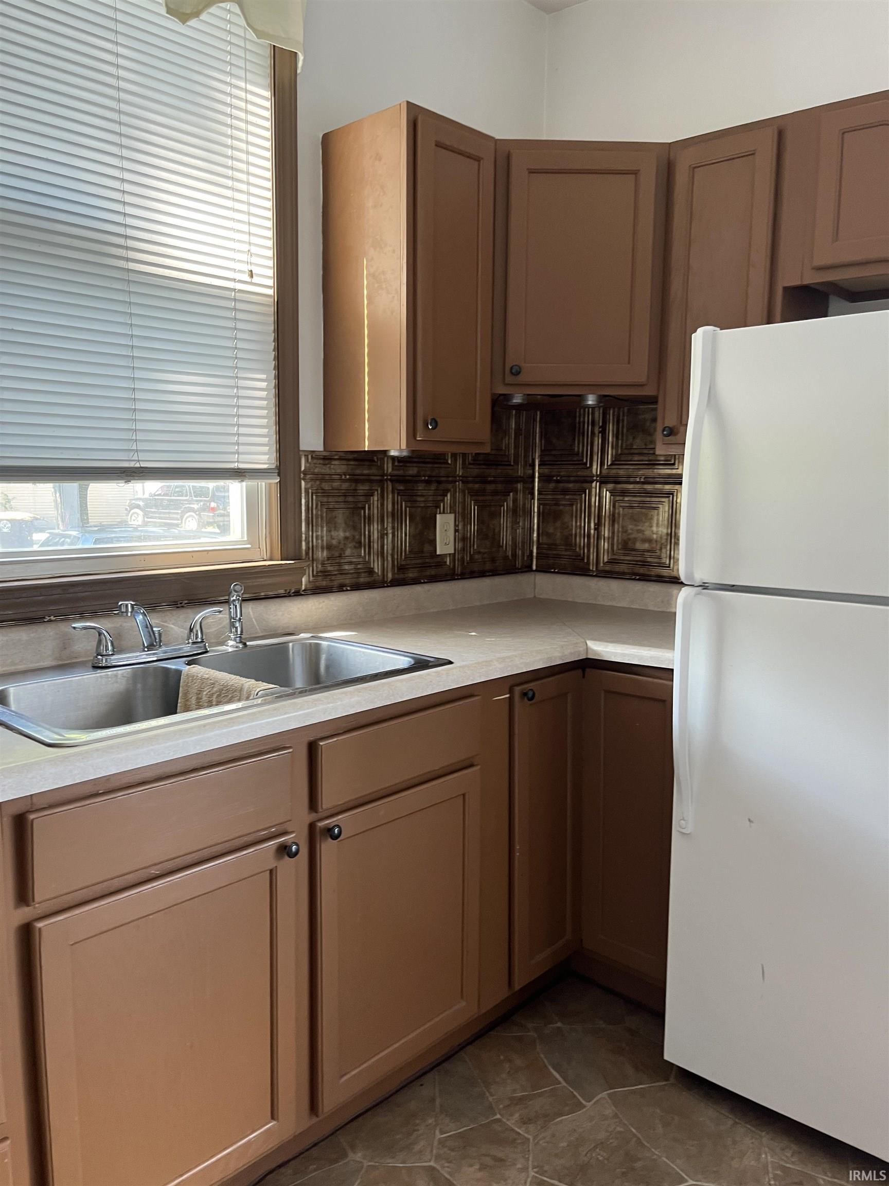 Kitchen with freestanding refrigerator, light countertops, and backsplash