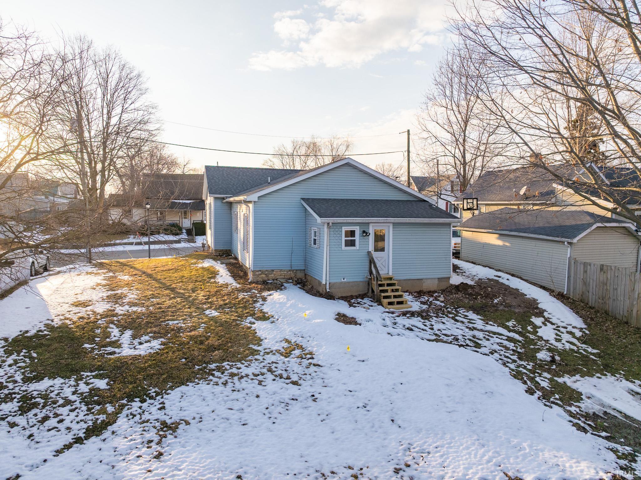 Snow covered house featuring entry steps and a shingled roof