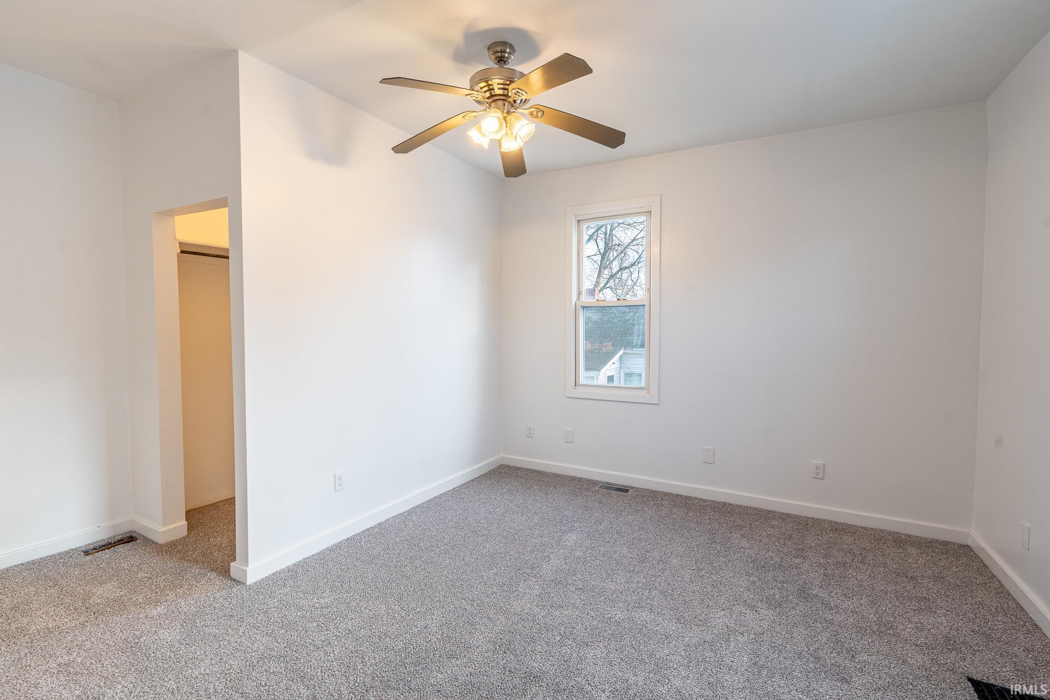 Unfurnished bedroom with light colored carpet and ceiling fan