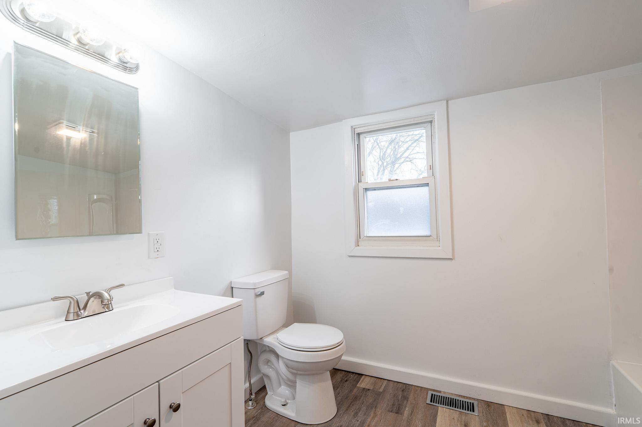 Full bathroom featuring vanity and dark wood-style floors