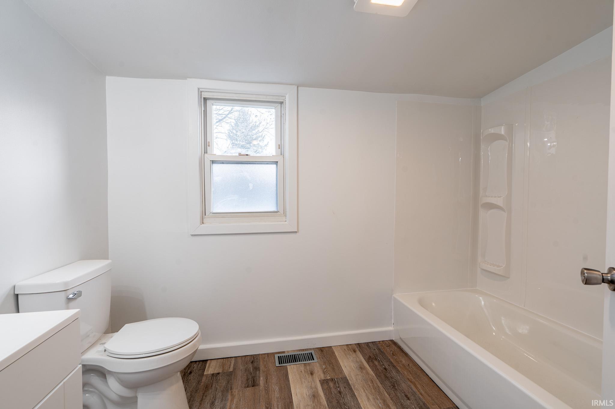 Full bath with dark wood finished floors, vanity, and shower / tub combination