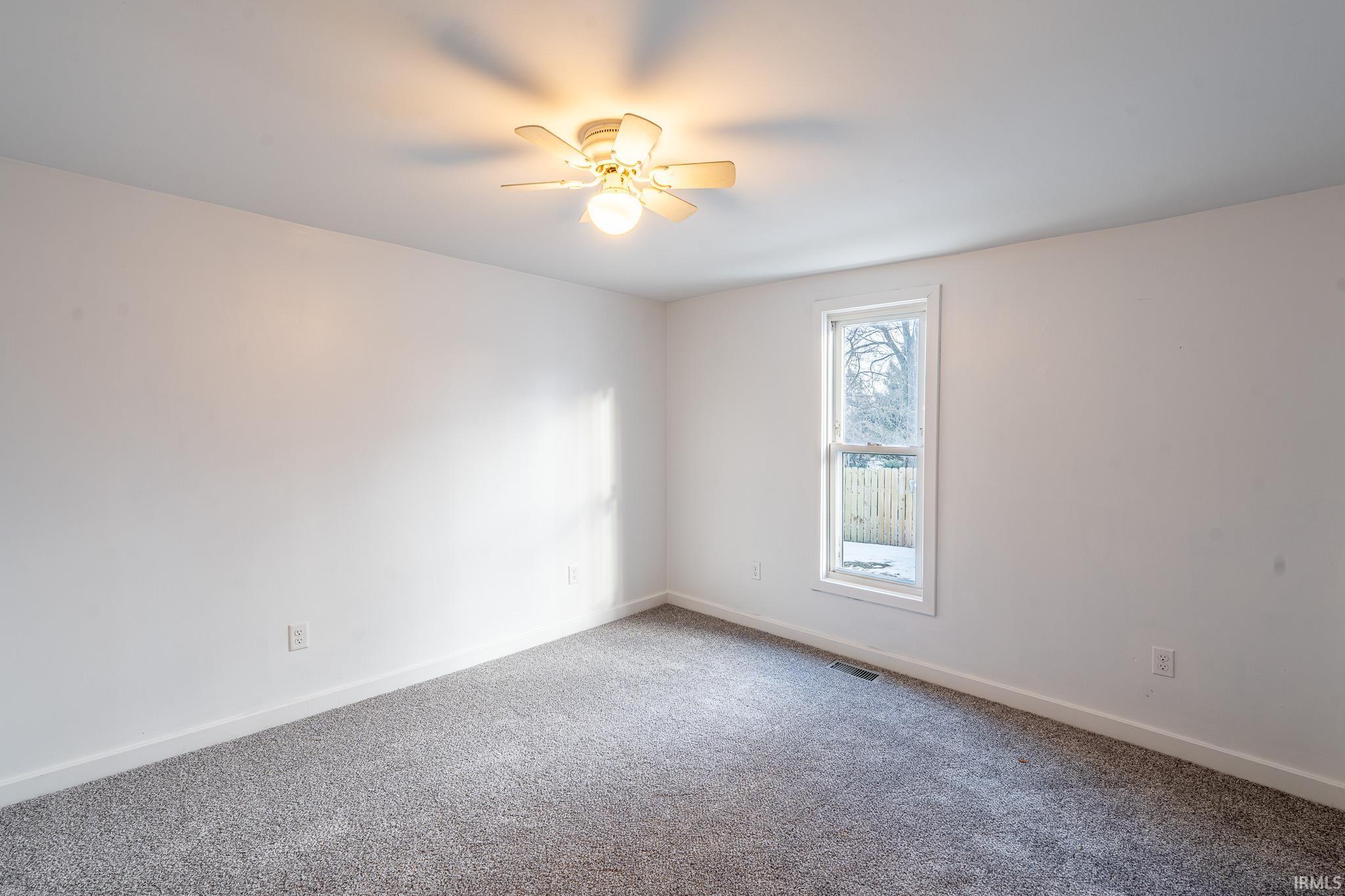 Carpeted empty room featuring baseboards and ceiling fan