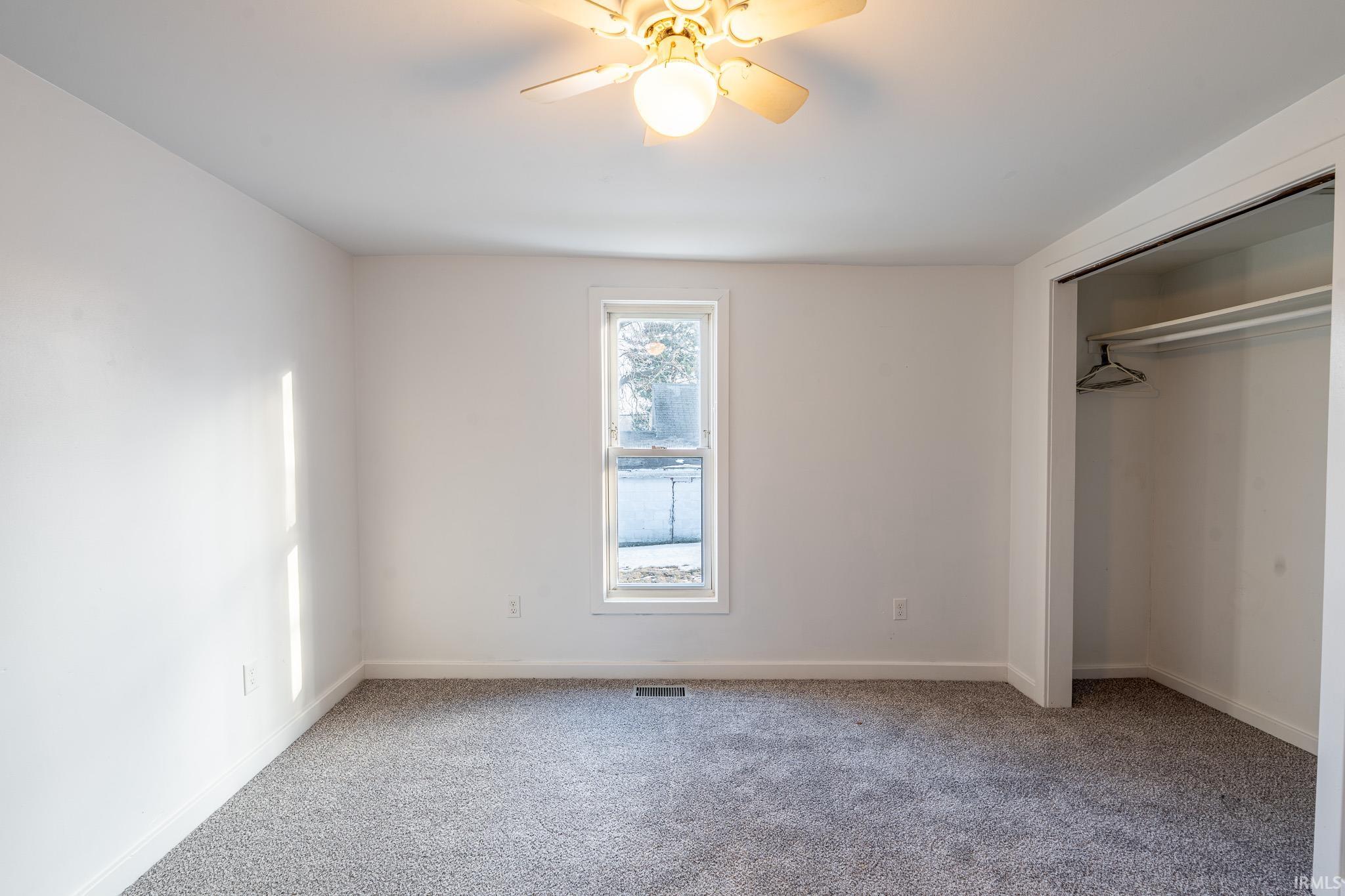 Unfurnished bedroom featuring light carpet, a closet, and ceiling fan