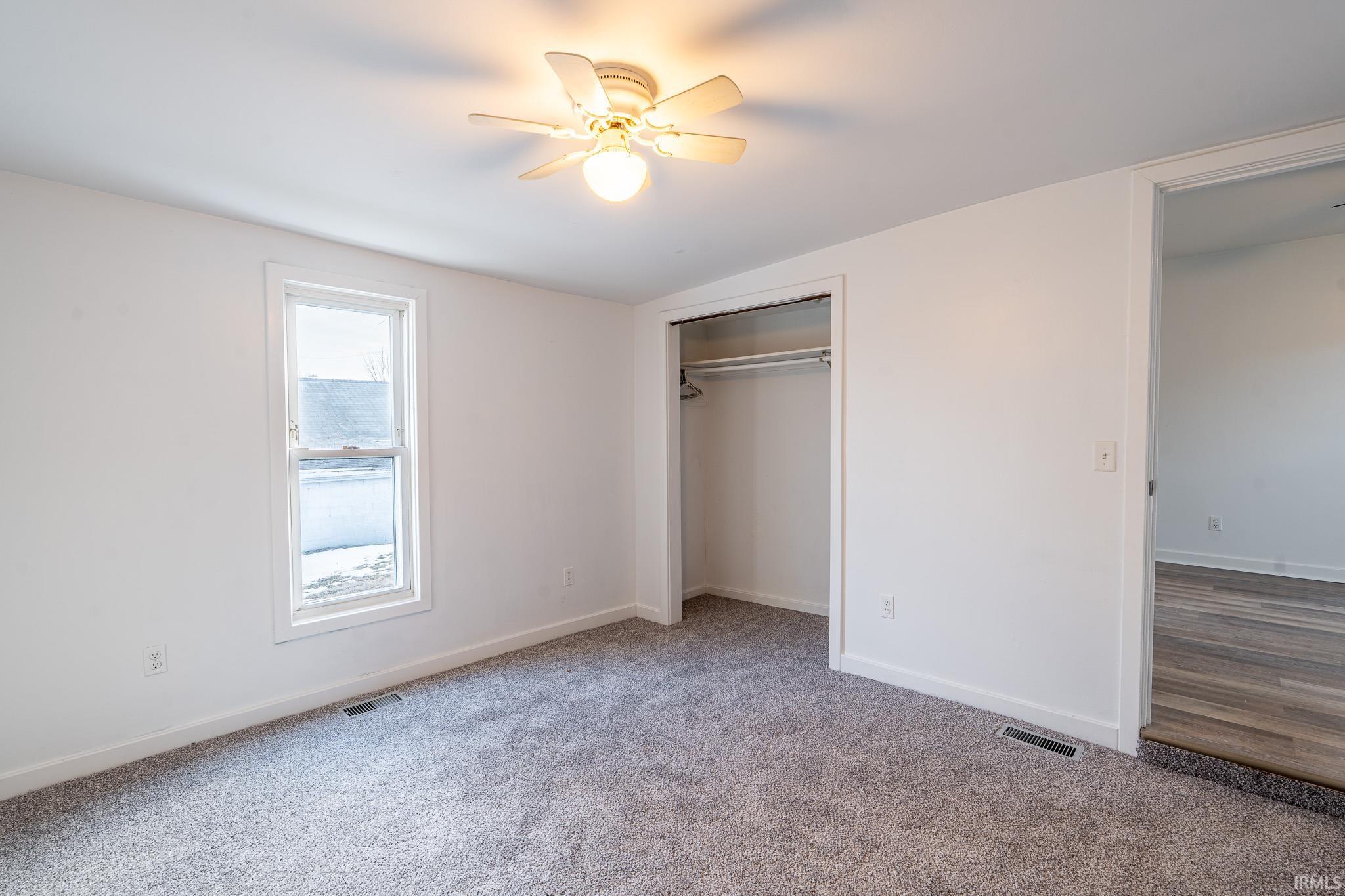 Unfurnished bedroom with lofted ceiling, ceiling fan, a closet, and carpet