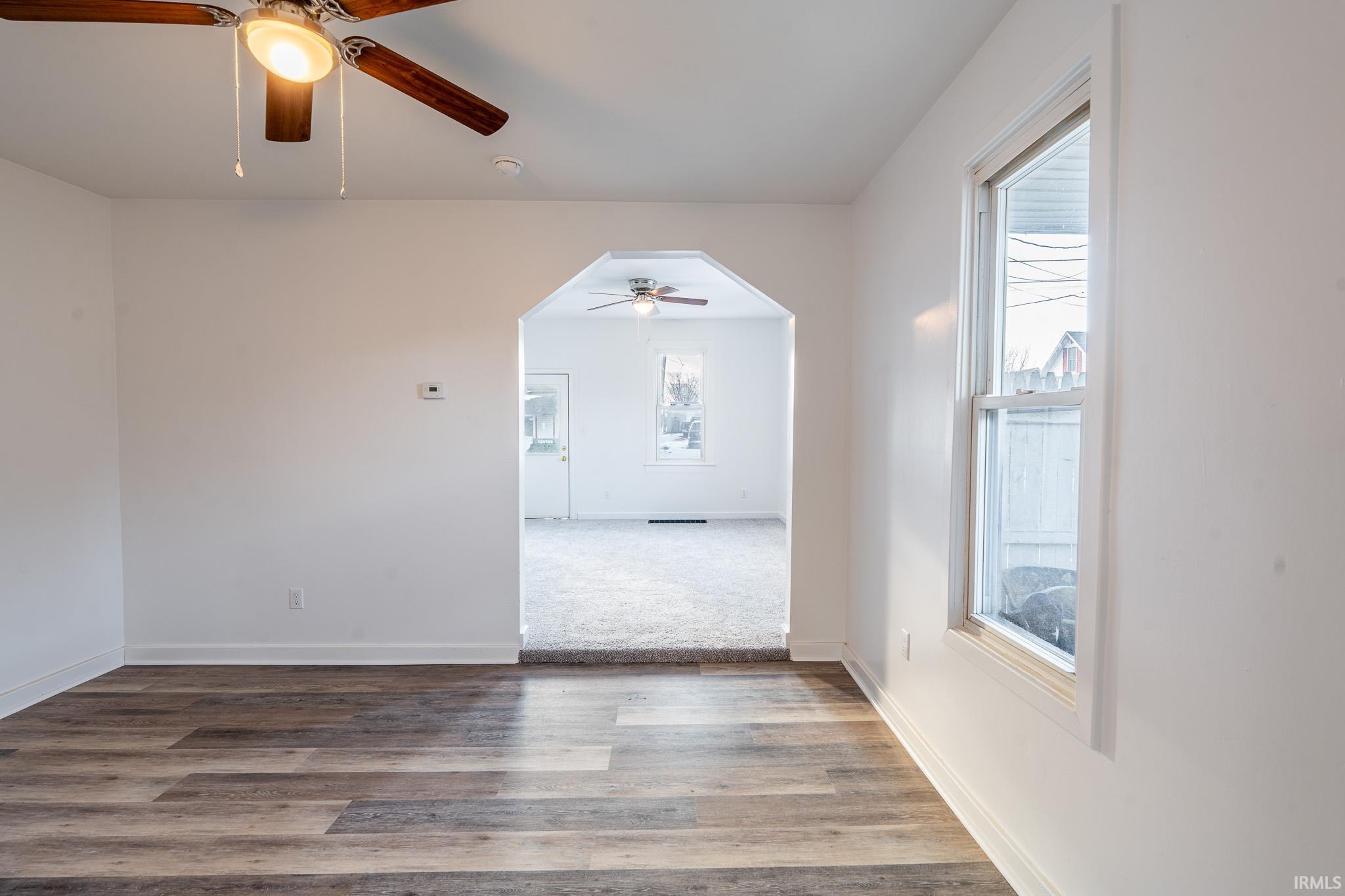 Spare room featuring wood finished floors, a ceiling fan, and arched walkways