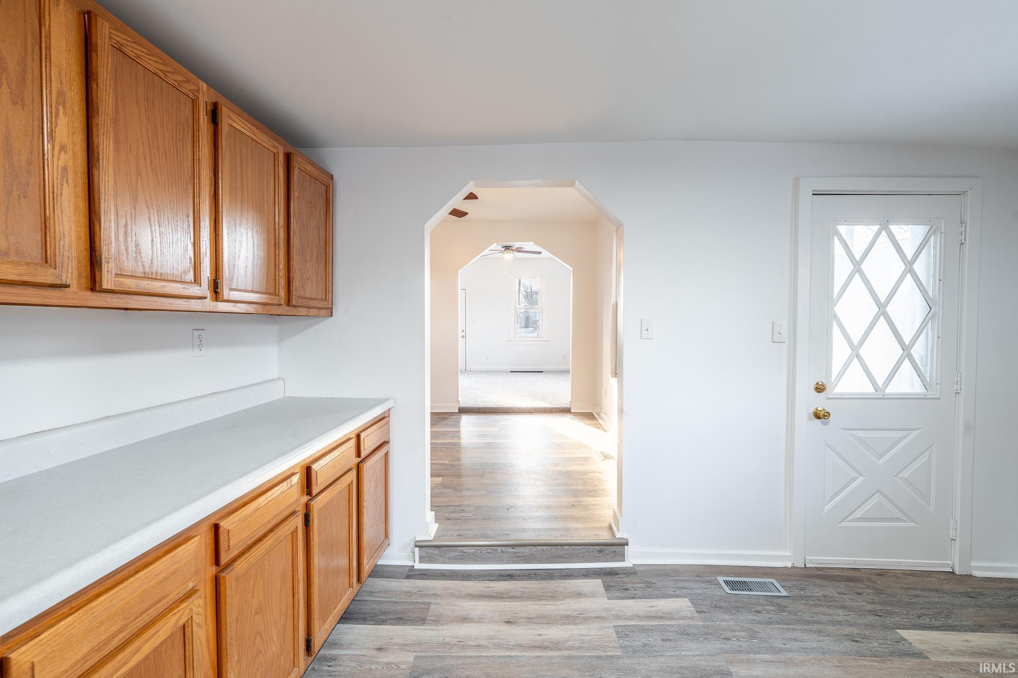 Kitchen with arched walkways, light countertops, light wood-type flooring, and wood finish cabinetry