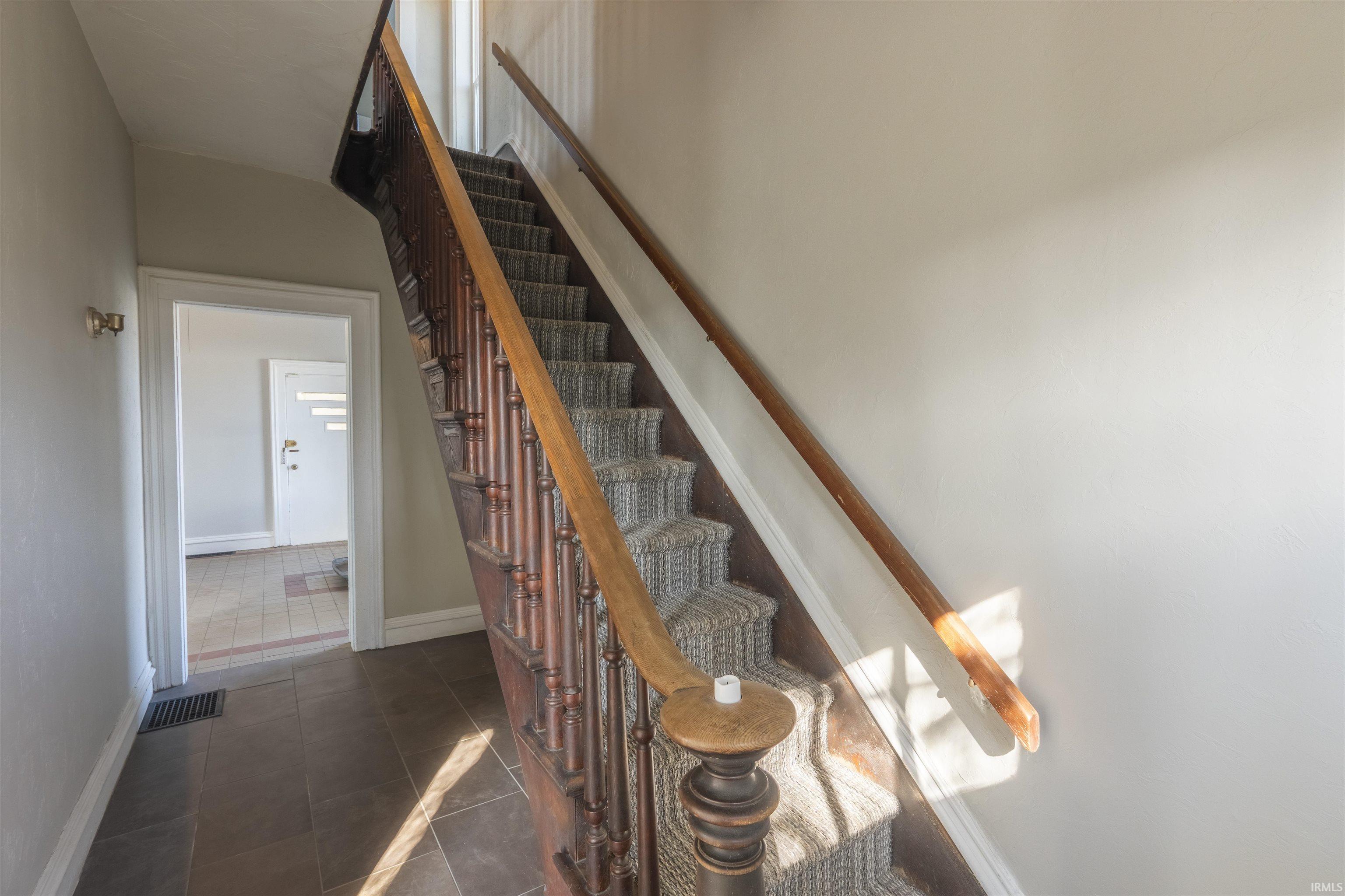 Stairway featuring tile patterned floors and baseboards