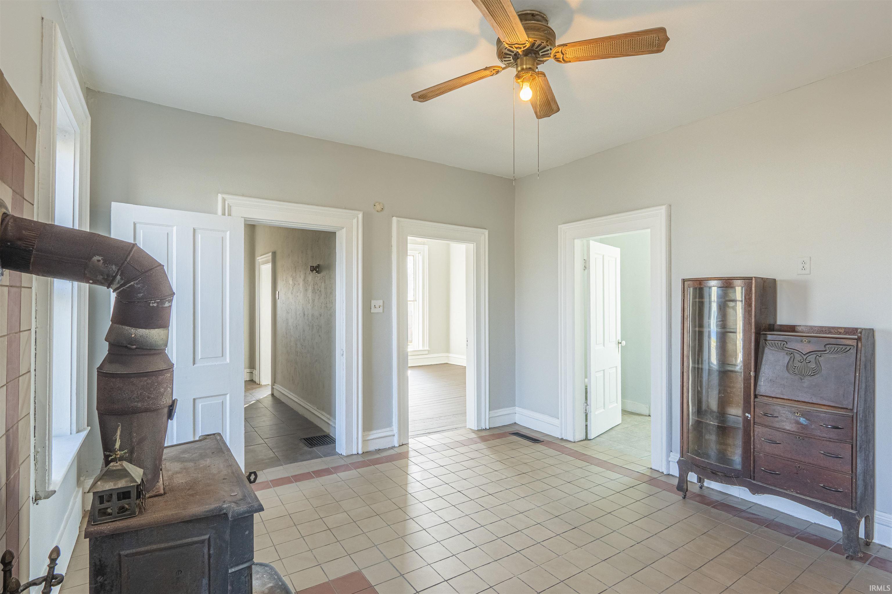 Living room with a wood stove, ceiling fan, and light tile patterned floors