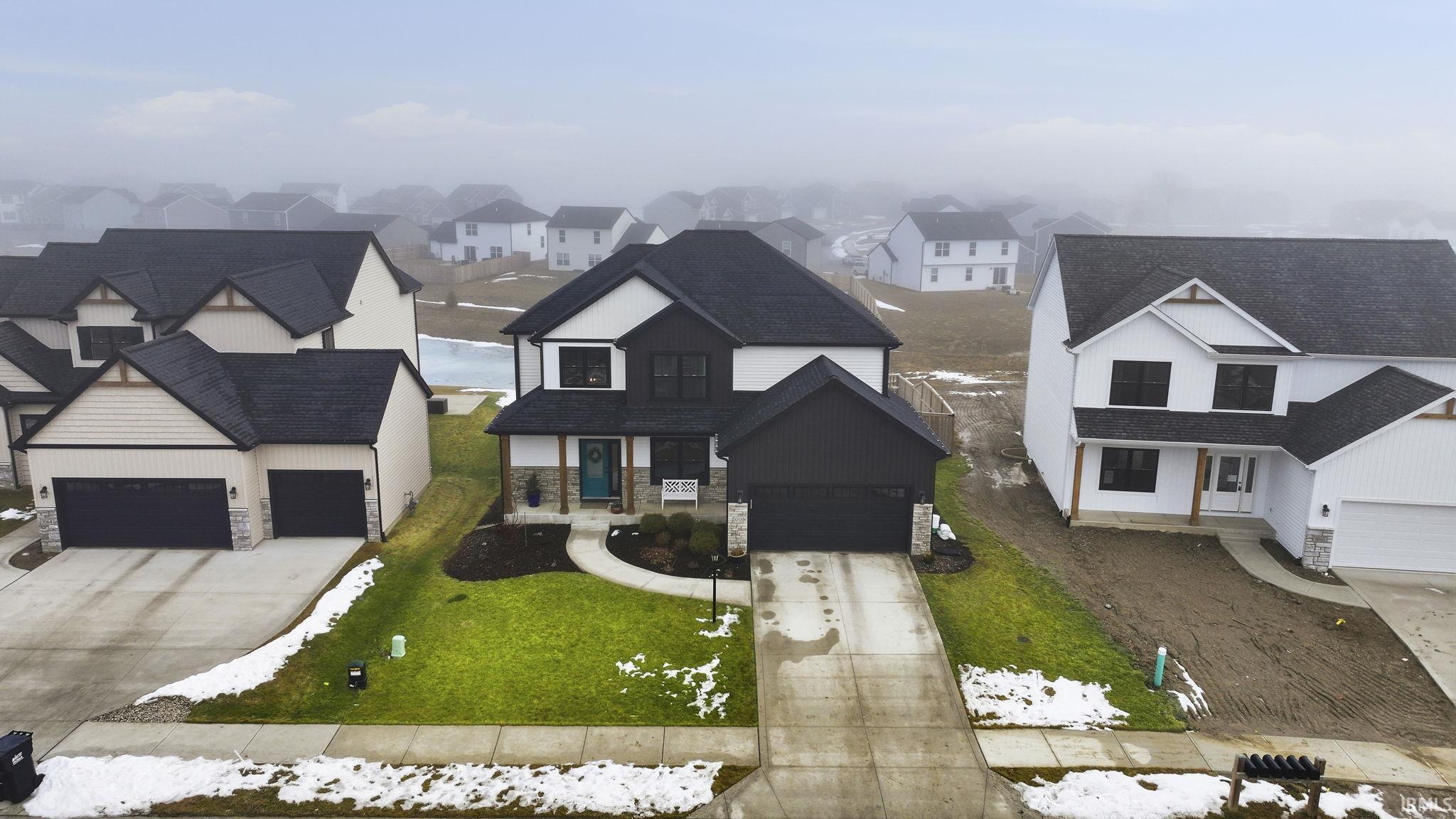 Modern farmhouse featuring stone siding, concrete driveway, and a residential view