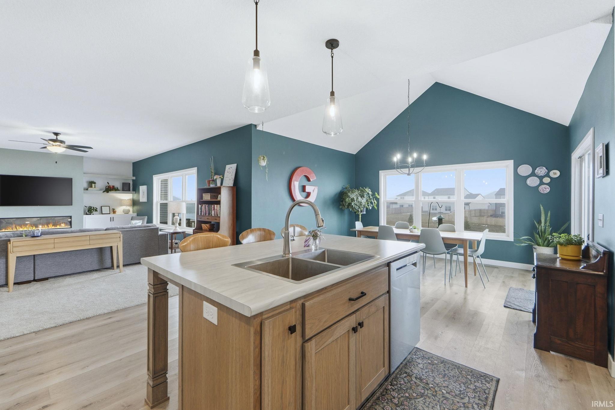 Kitchen featuring light countertops, light wood-style flooring, open floor plan, hanging light fixtures, and ceiling fan