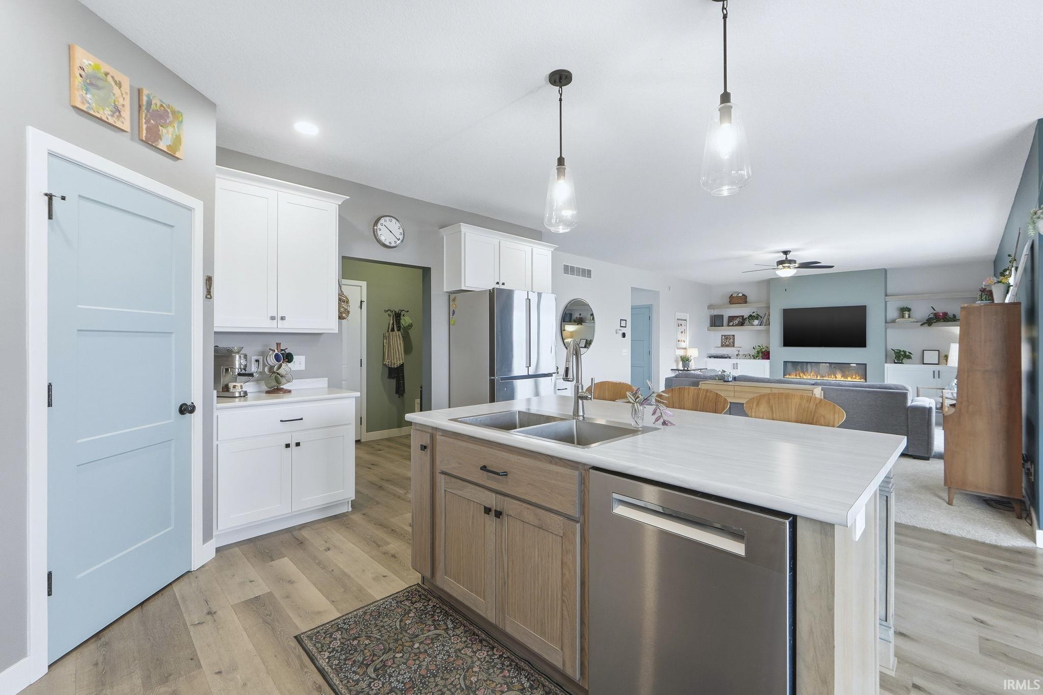 Two tone kitchen featuring stainless steel appliances, light countertops, hanging light fixtures, open floor plan, and two tone cabinets