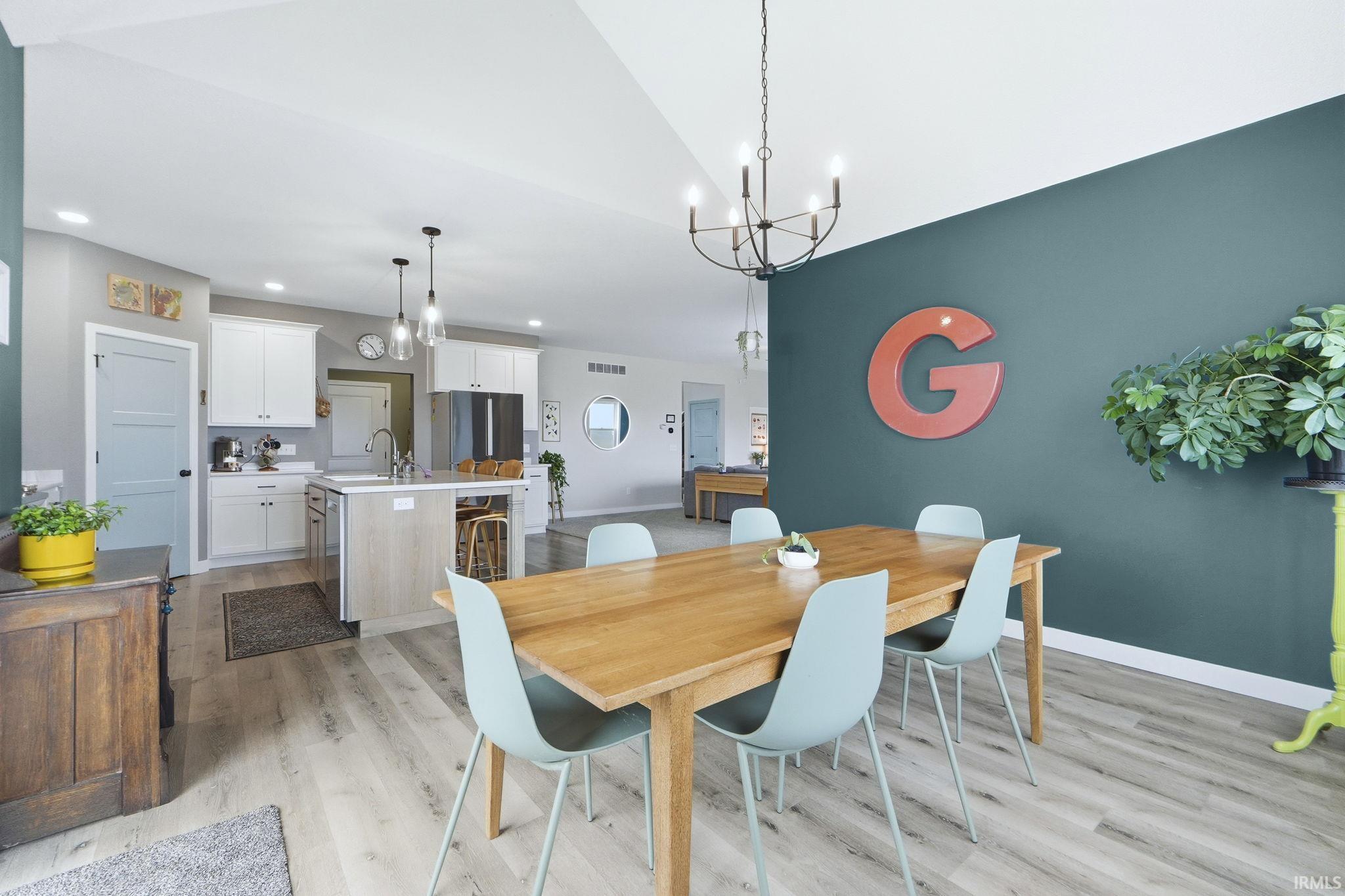Dining room with light wood-style floors, a chandelier, and vaulted ceiling
