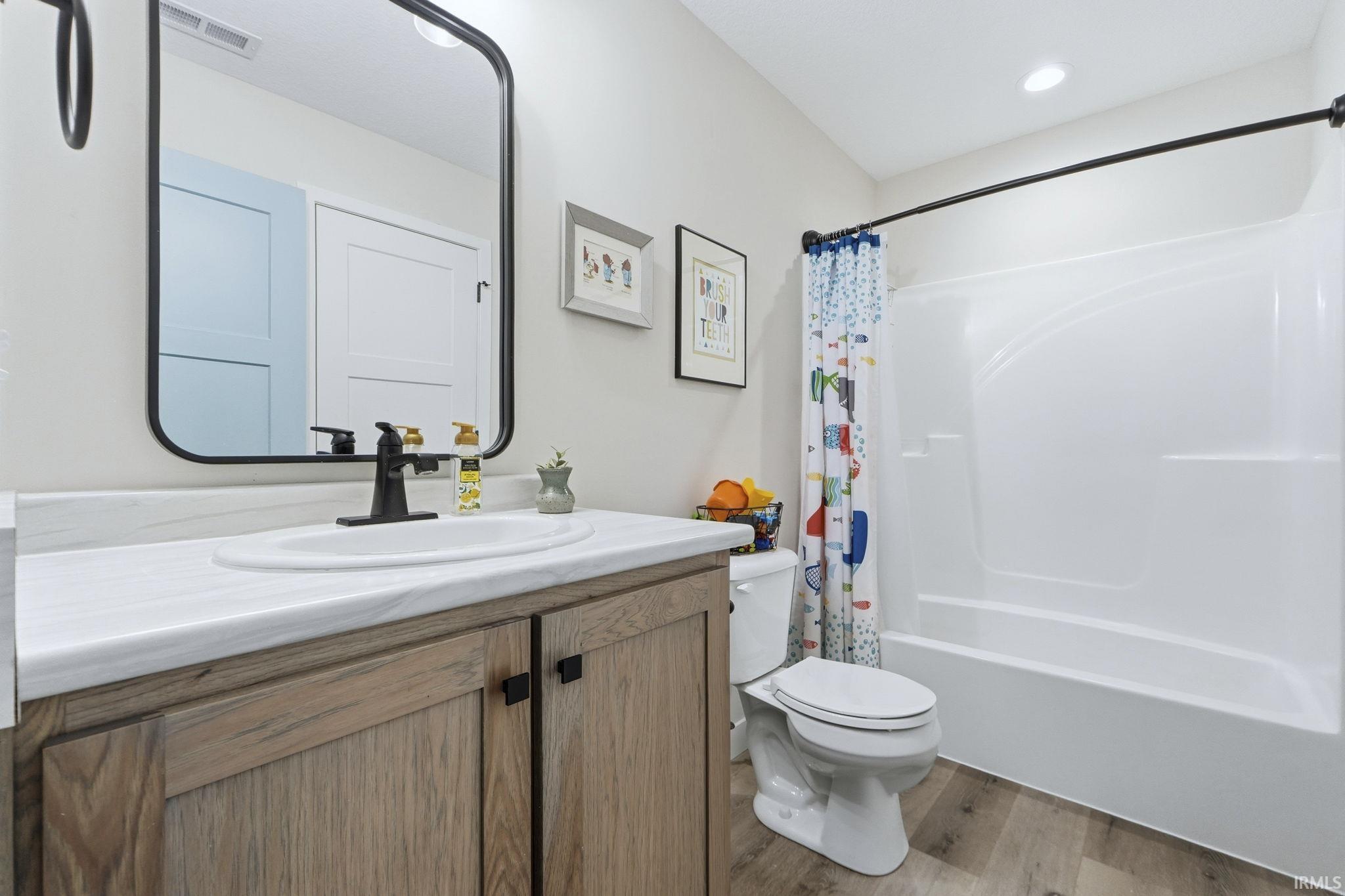 Bathroom with shower / tub combo with curtain, vanity, and light wood-type flooring