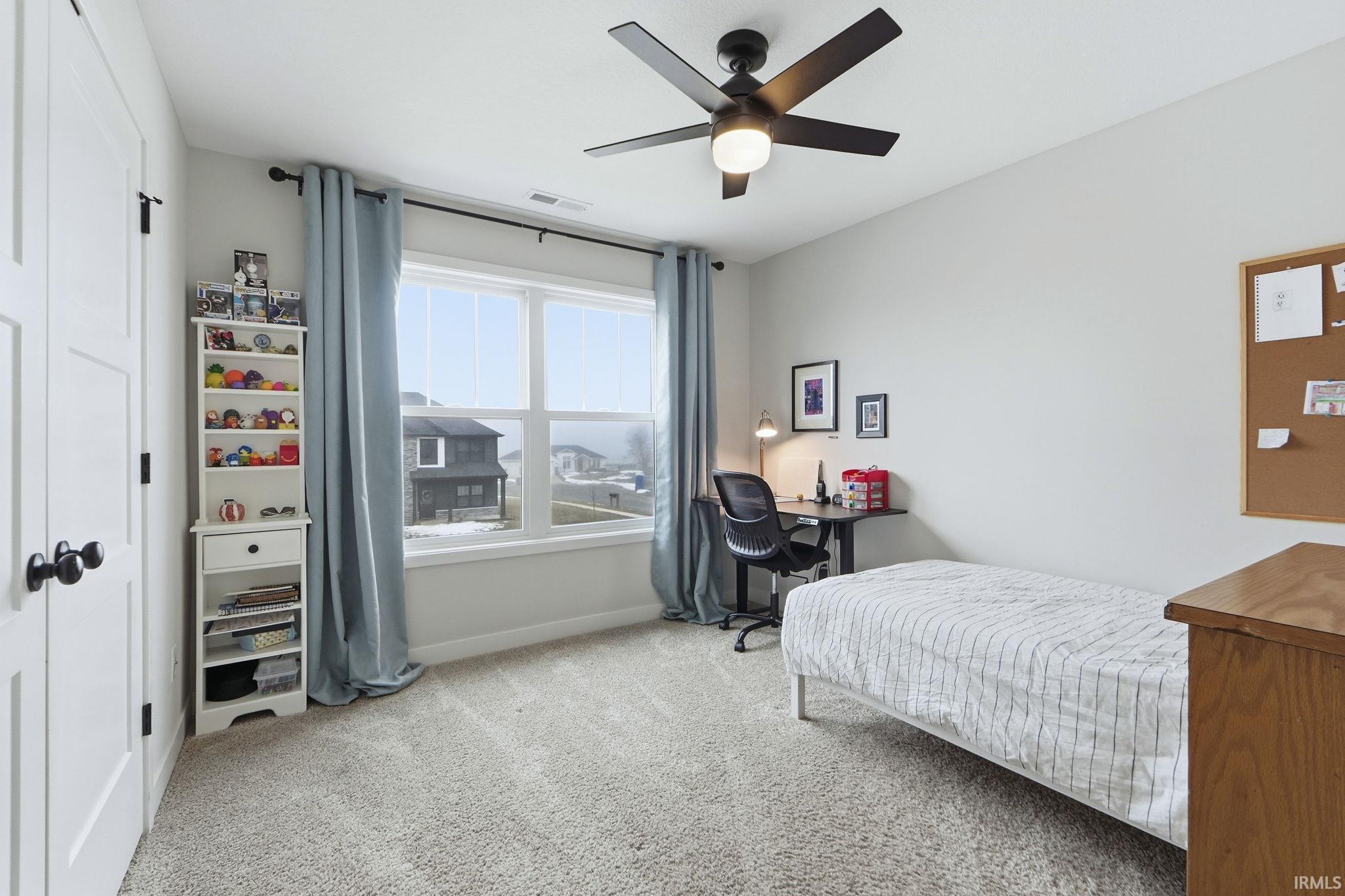 Bedroom featuring light carpet, a desk, a ceiling fan, and a closet