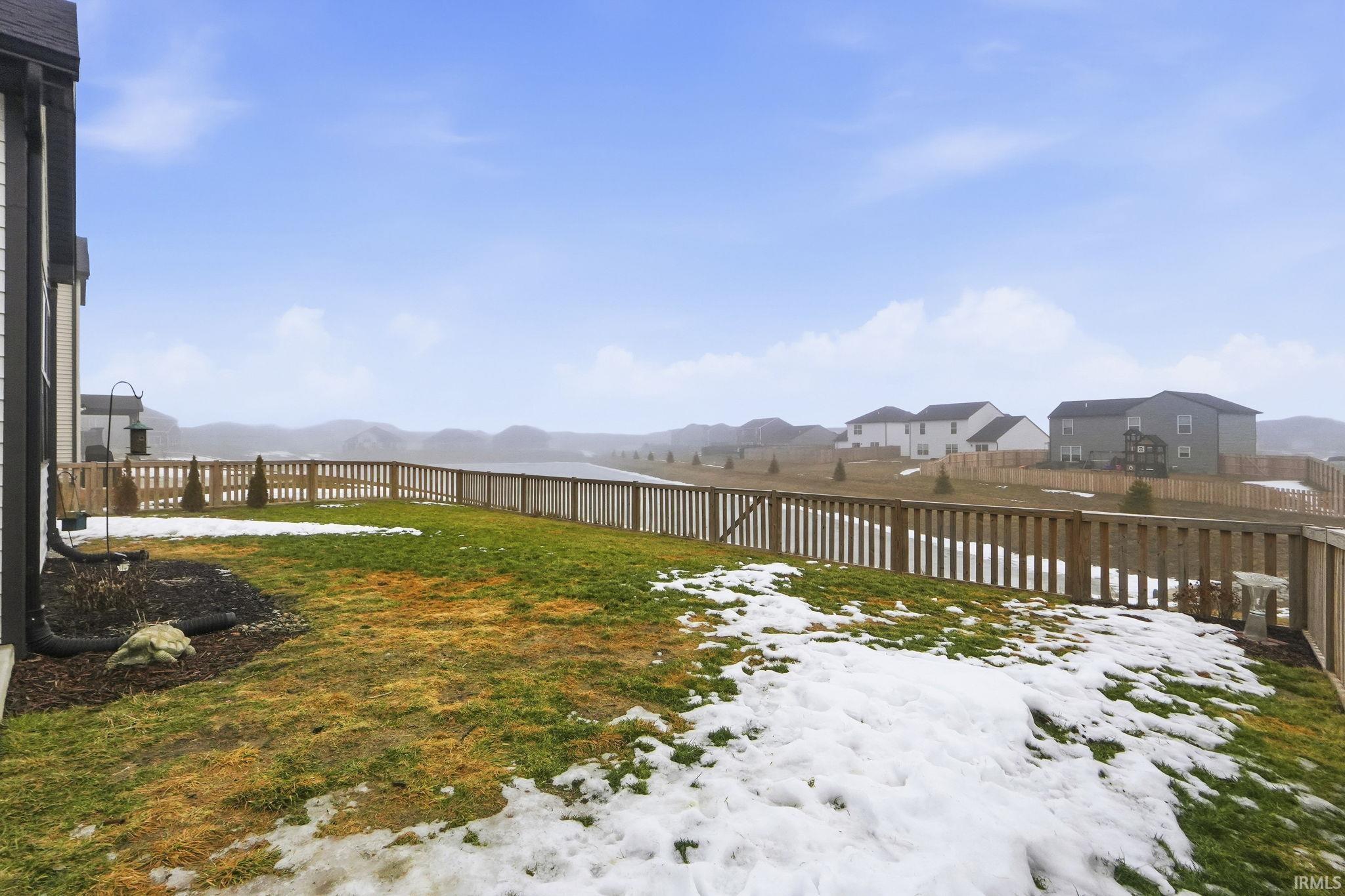 Yard layered in snow with a fenced backyard, a residential view, and a mountain view