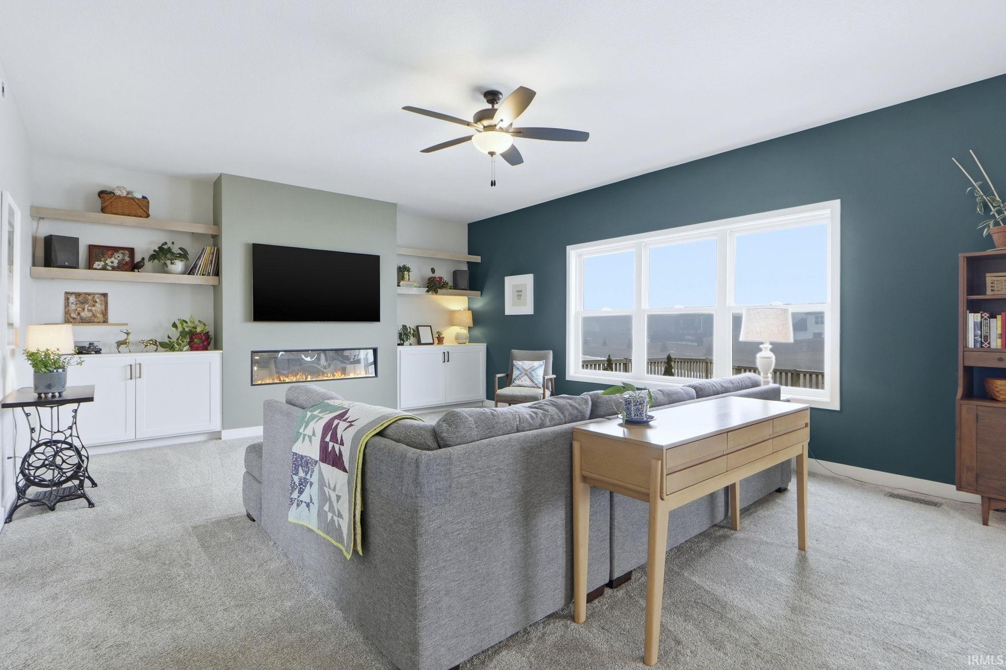 Living room featuring light carpet, a ceiling fan, and a glass covered fireplace