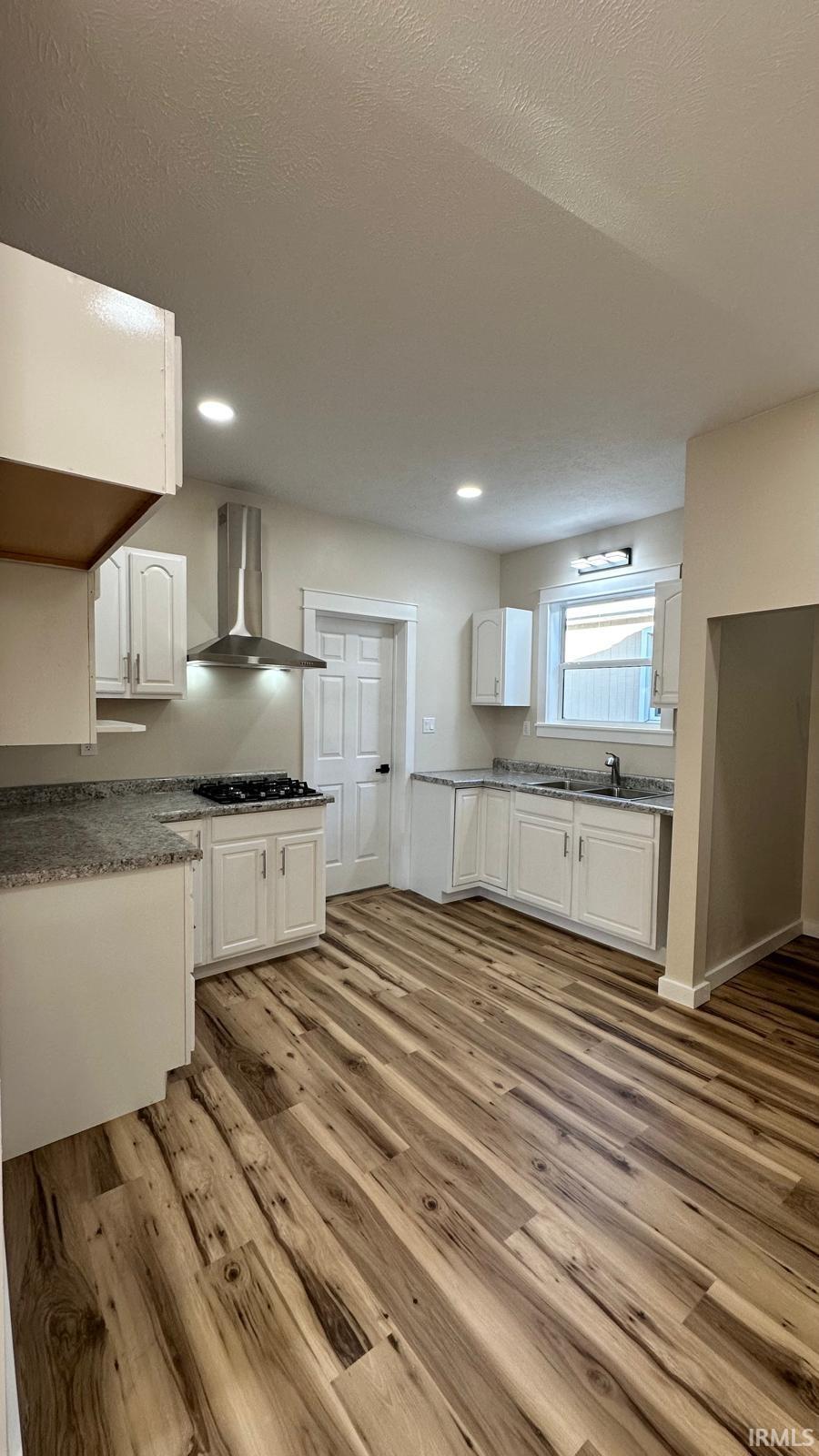 Kitchen featuring white cabinets, light wood-style flooring, a textured ceiling, recessed lighting, and black gas cooktop
