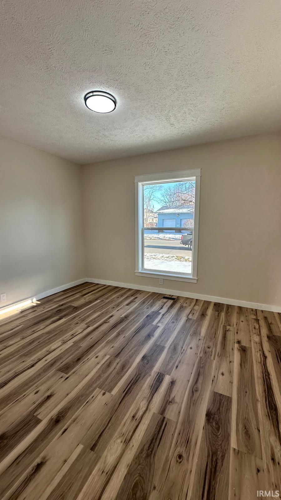 Unfurnished room with a textured ceiling and wood finished floors