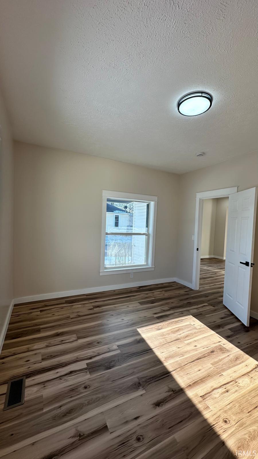 Unfurnished room with dark wood-type flooring and a textured ceiling