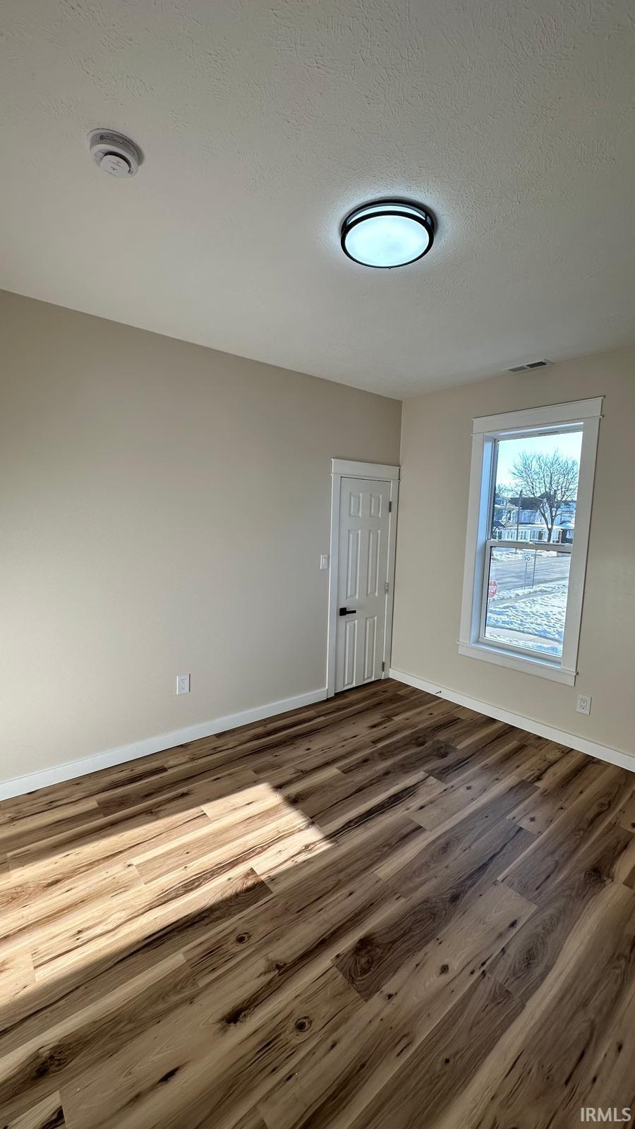 Unfurnished room with wood finished floors and a textured ceiling