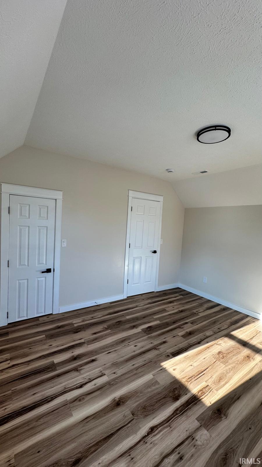Unfurnished bedroom with dark wood-type flooring and baseboards