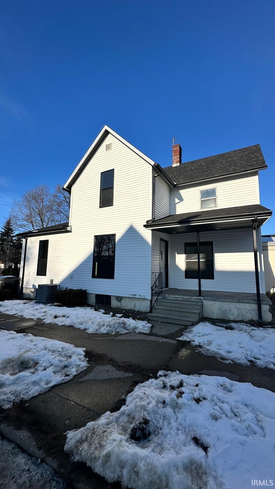 View of front of home featuring a chimney and covered porch