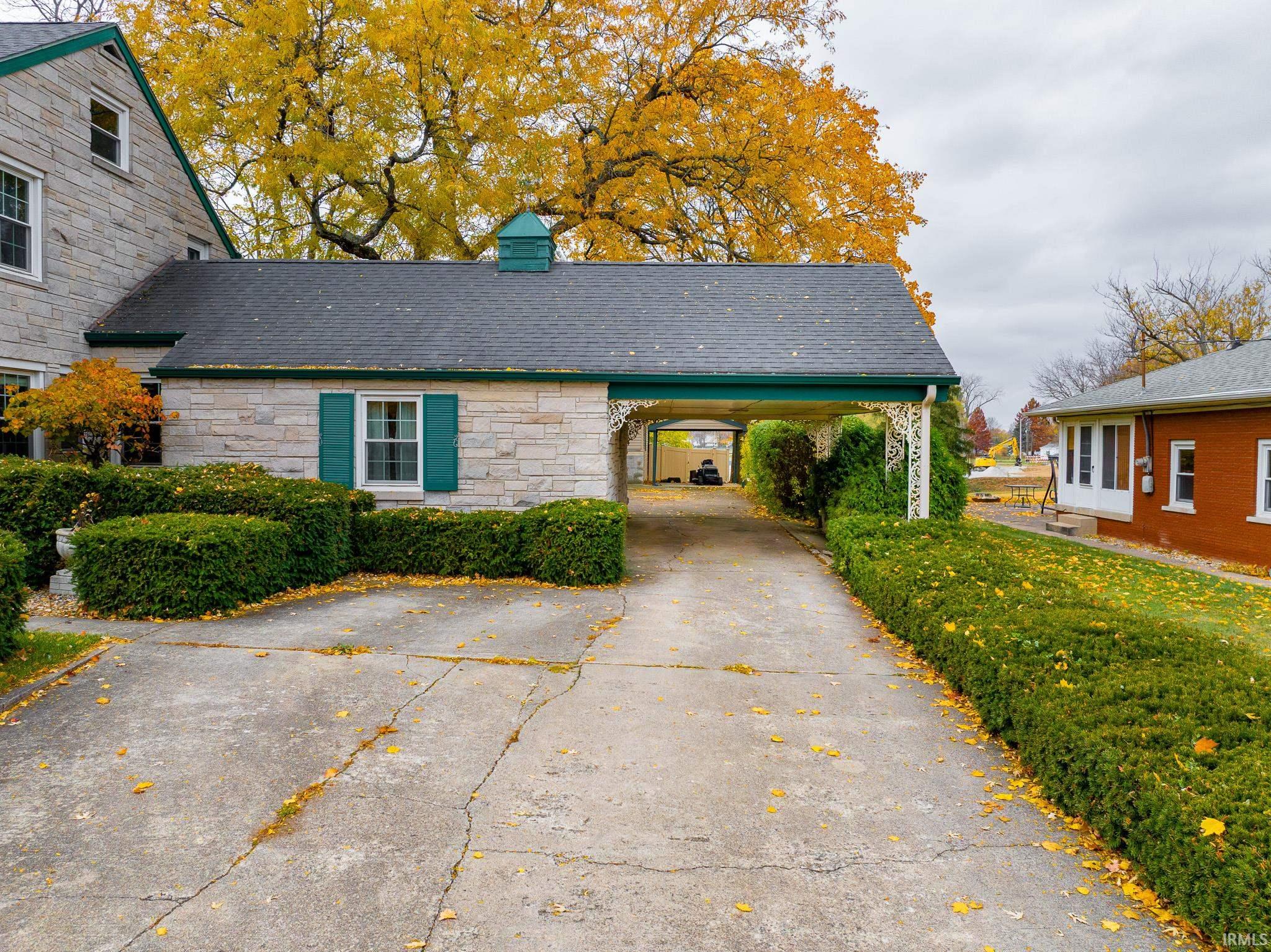 View of front of property with stone siding, concrete driveway, and a chimney