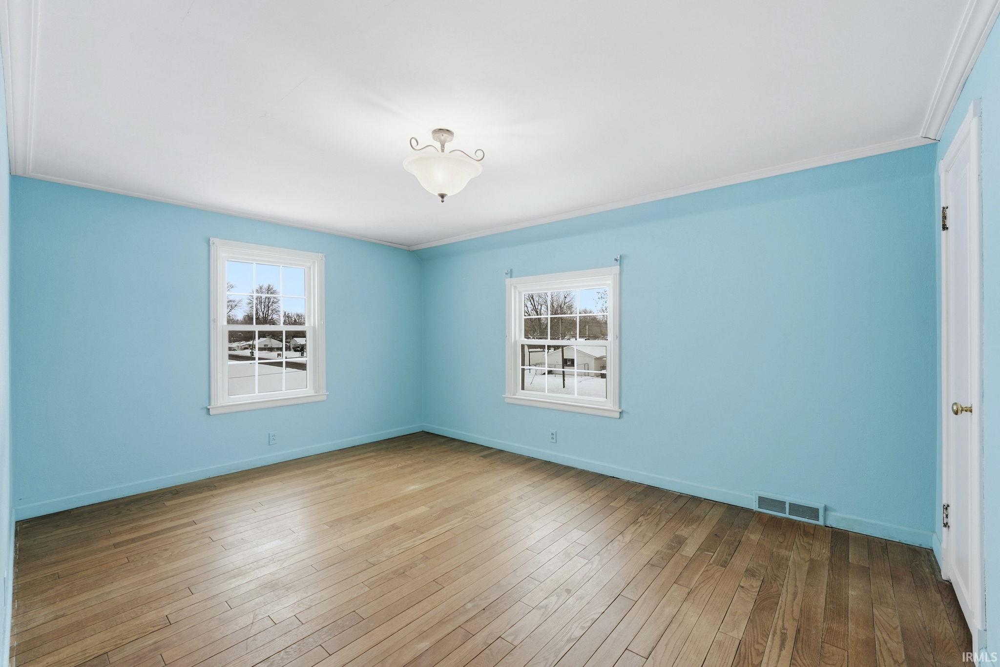 Spare room with crown molding and light wood-style floors