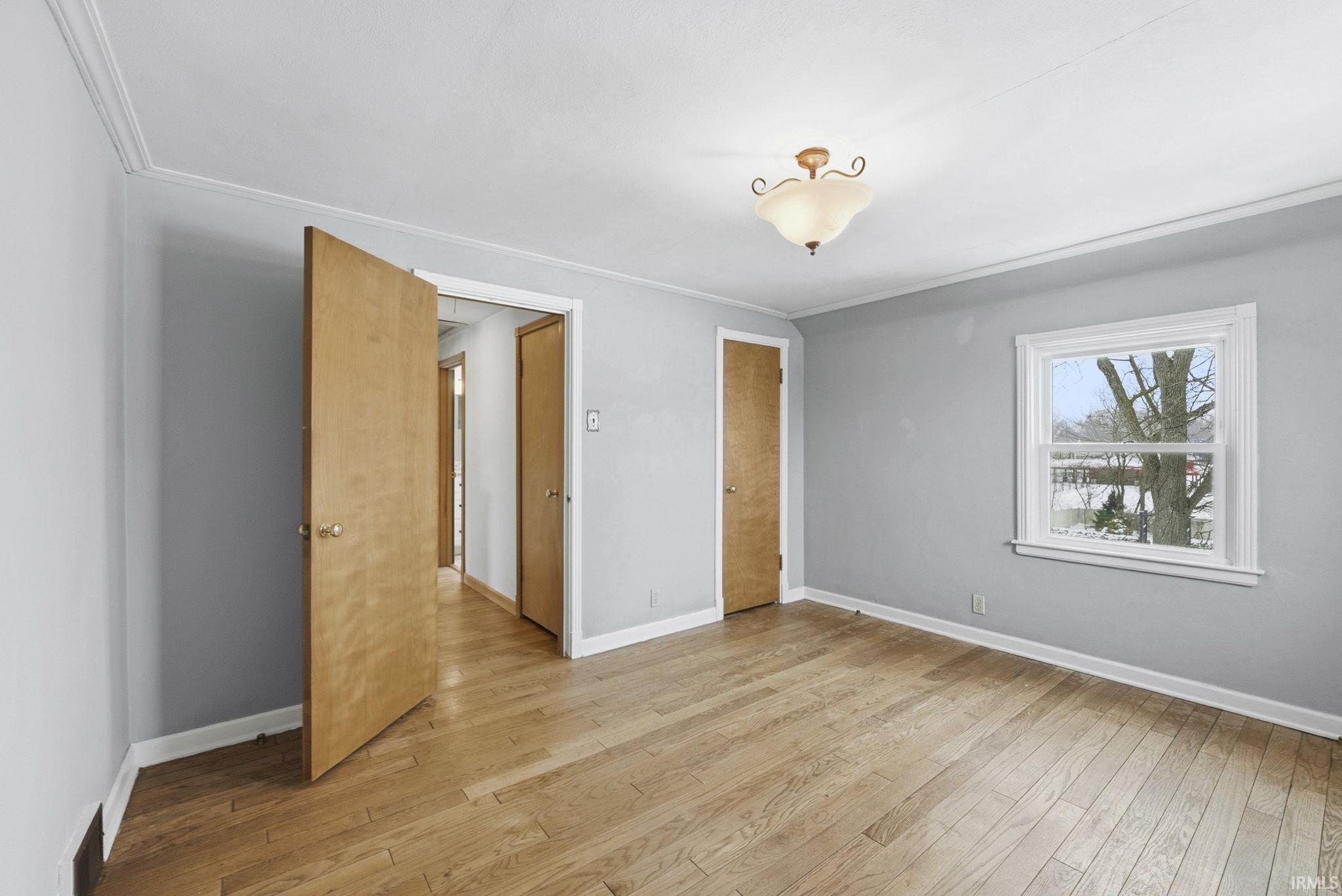 Unfurnished bedroom with ornamental molding and light wood-style floors