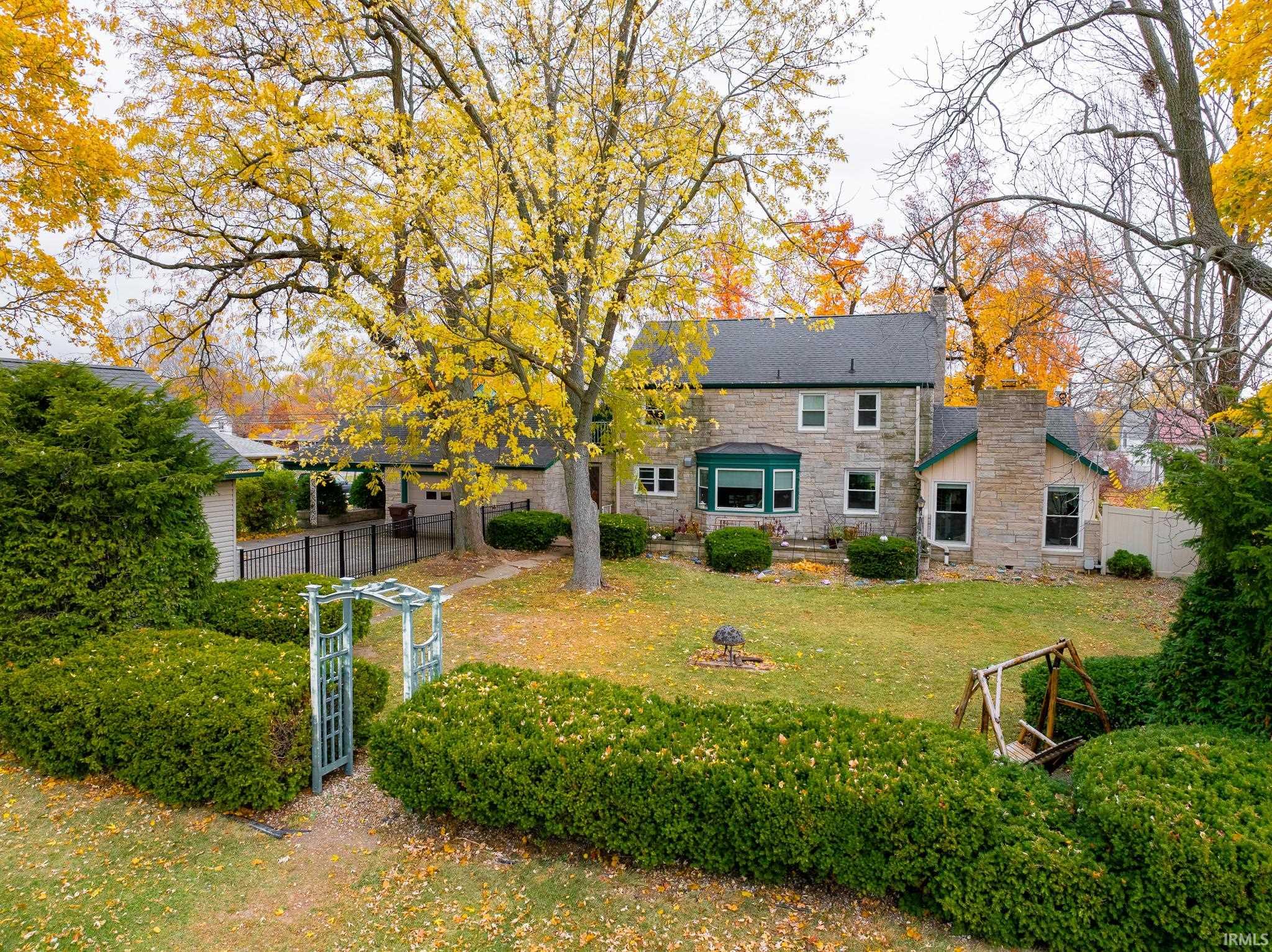 Rear view of property featuring stone siding and a chimney