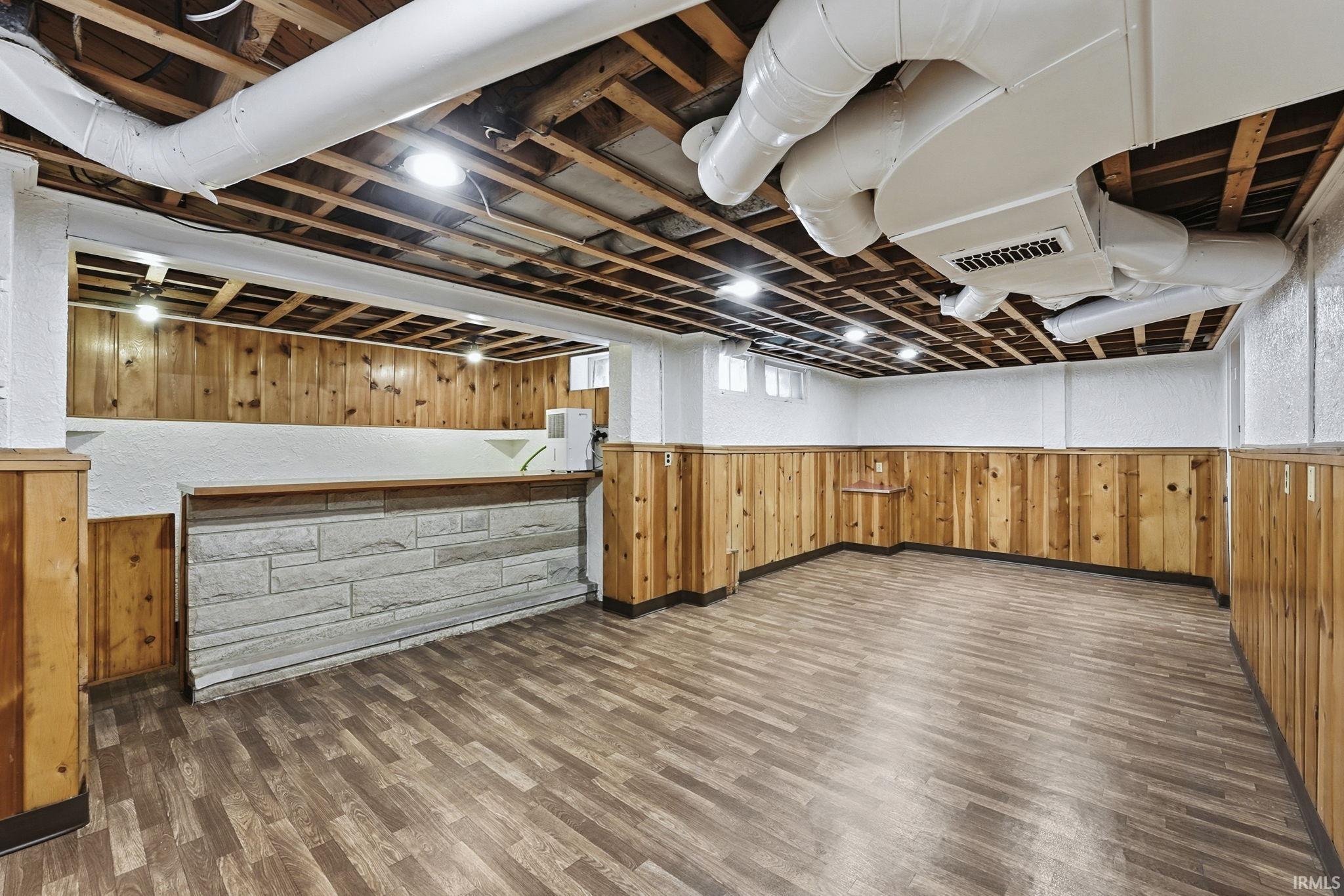 Basement with wood walls, dark wood-style floors, and wainscoting