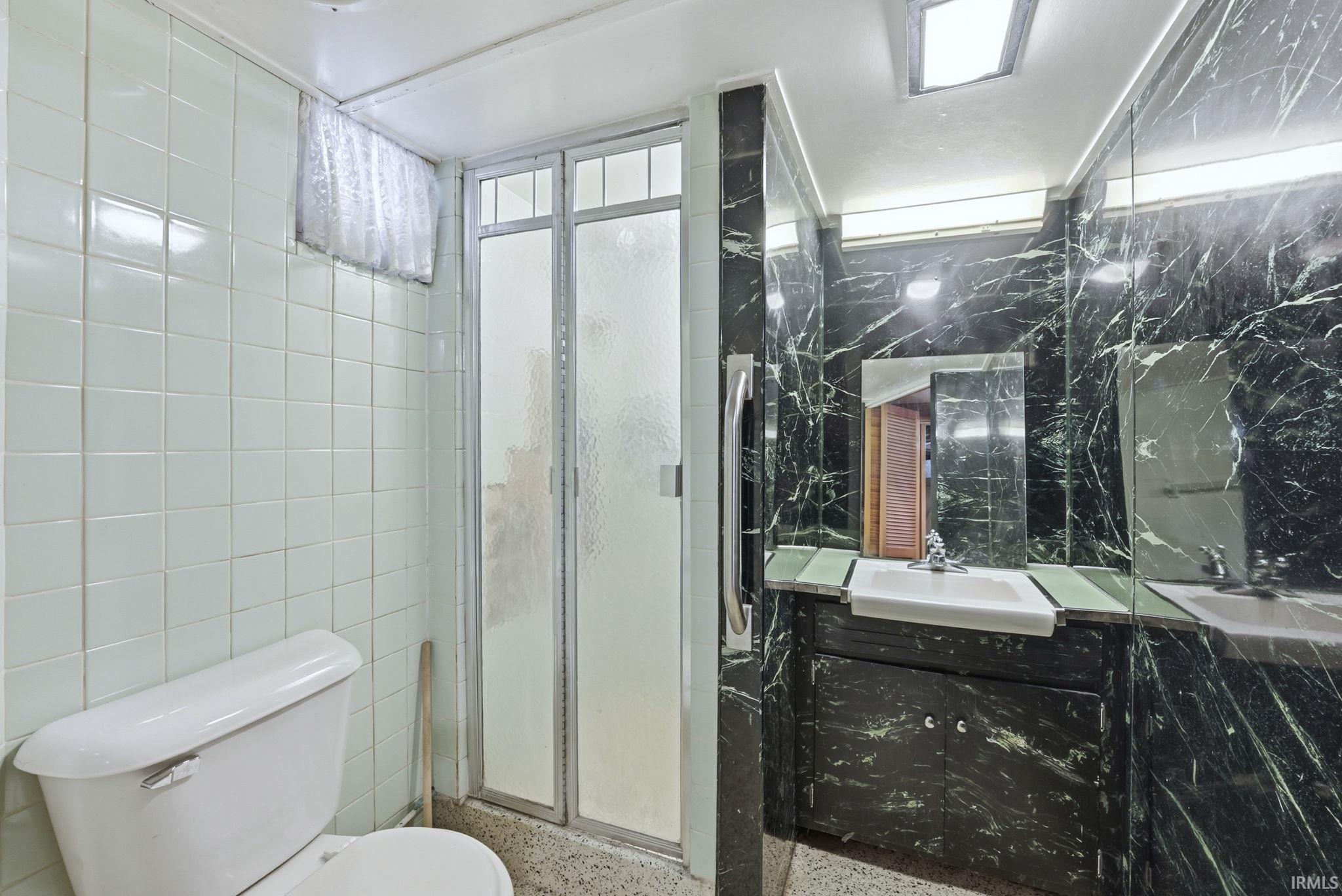 Bathroom with tile walls, vanity, a shower stall, and speckled floor