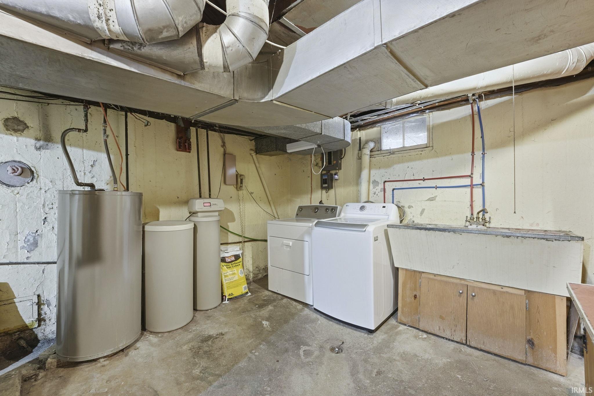 Laundry area with concrete flooring, washer and clothes dryer, and water heater