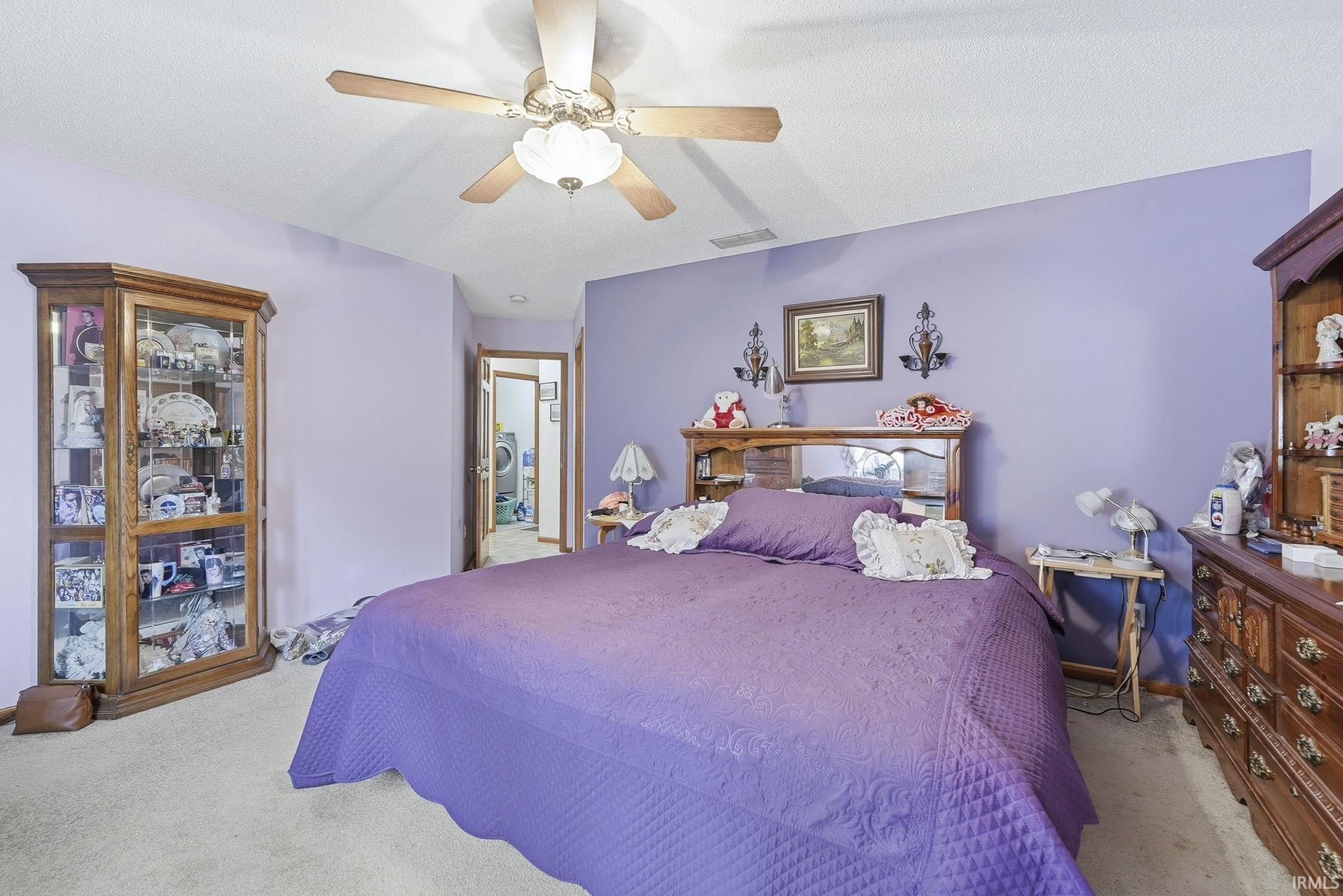 Bedroom featuring light colored carpet, a ceiling fan, and washer / dryer