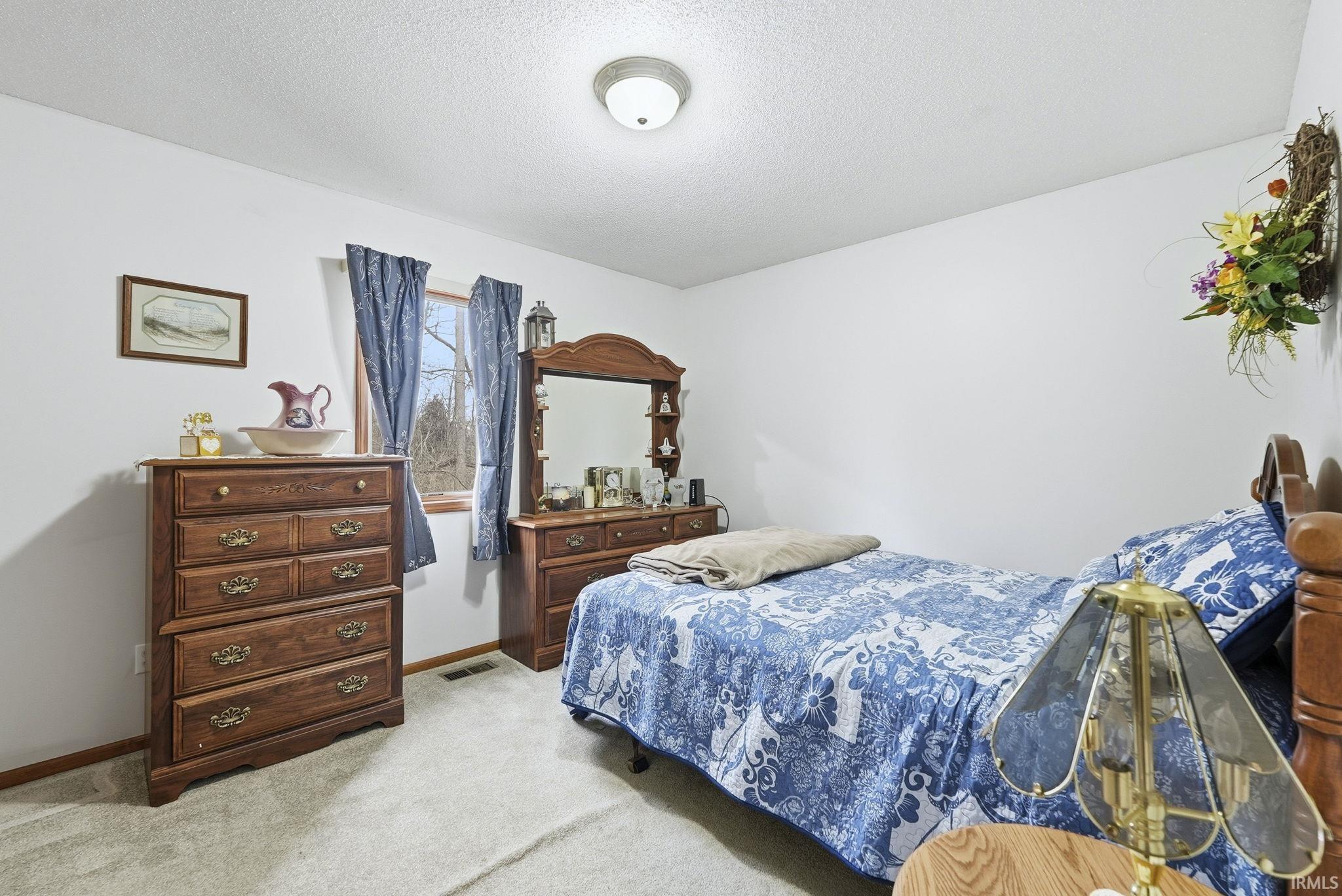 Bedroom featuring light carpet and a textured ceiling