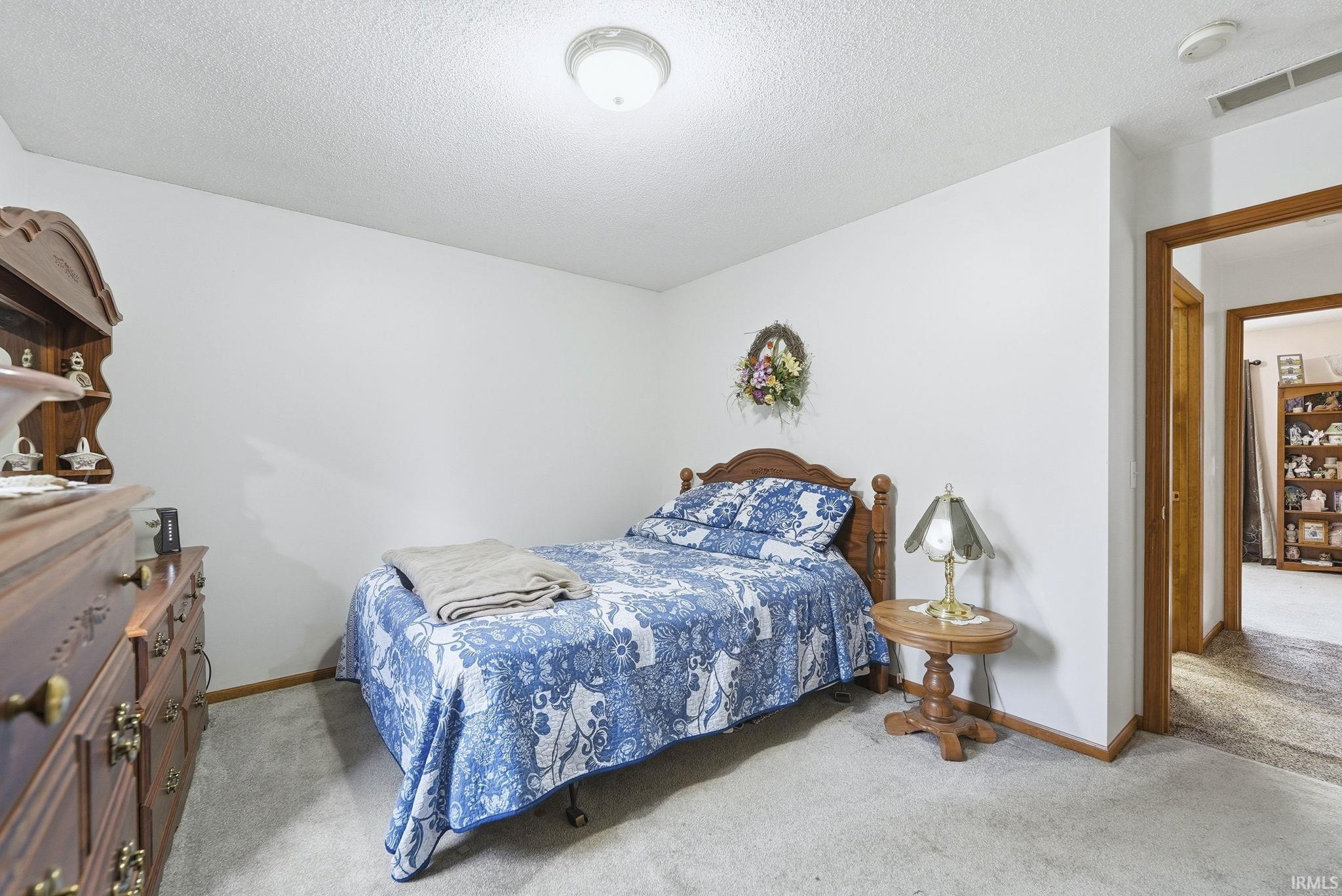 Bedroom with light colored carpet and a textured ceiling