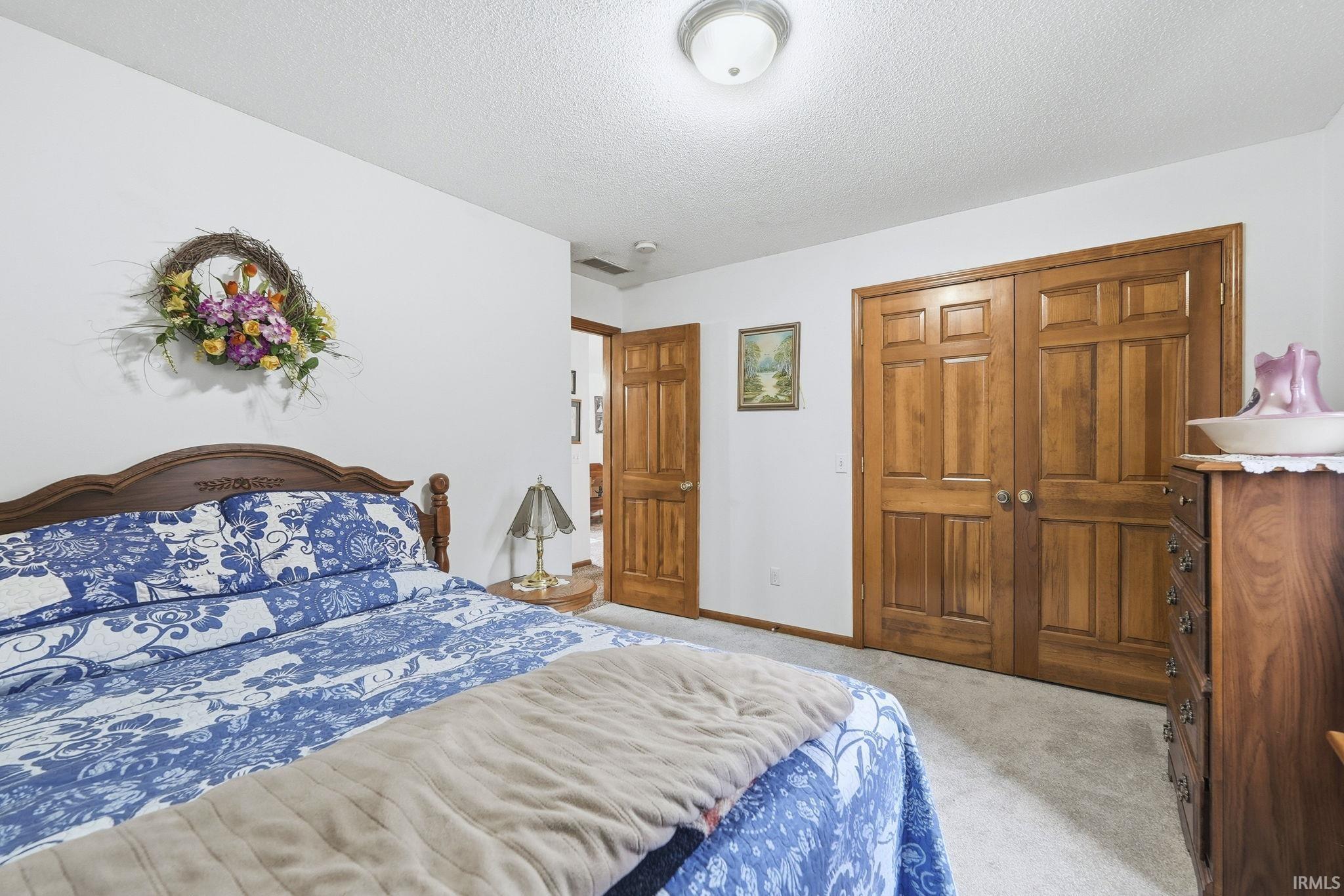 Bedroom with light carpet, a closet, and a textured ceiling