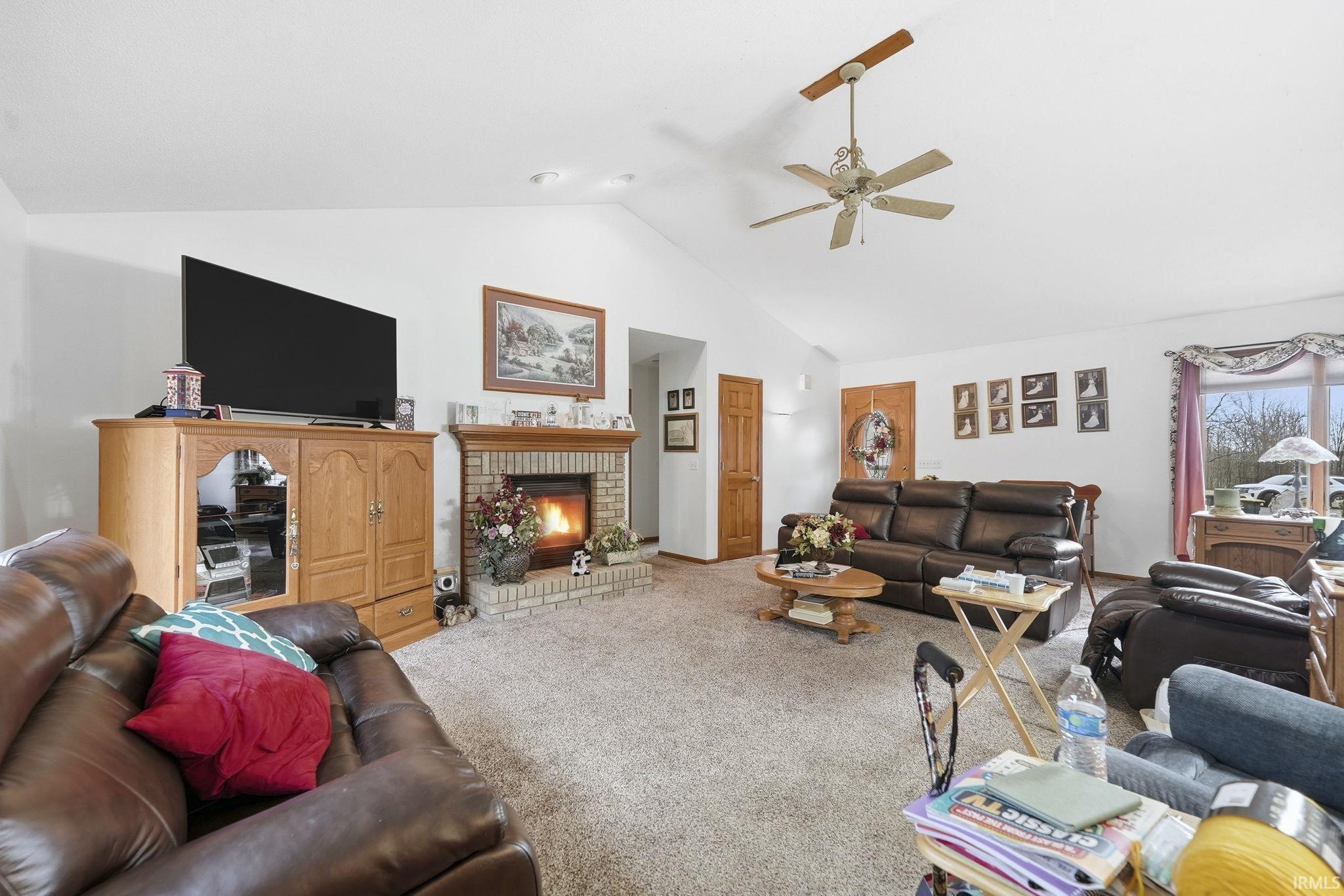 Living area featuring a fireplace, carpet, a high ceiling, and a ceiling fan