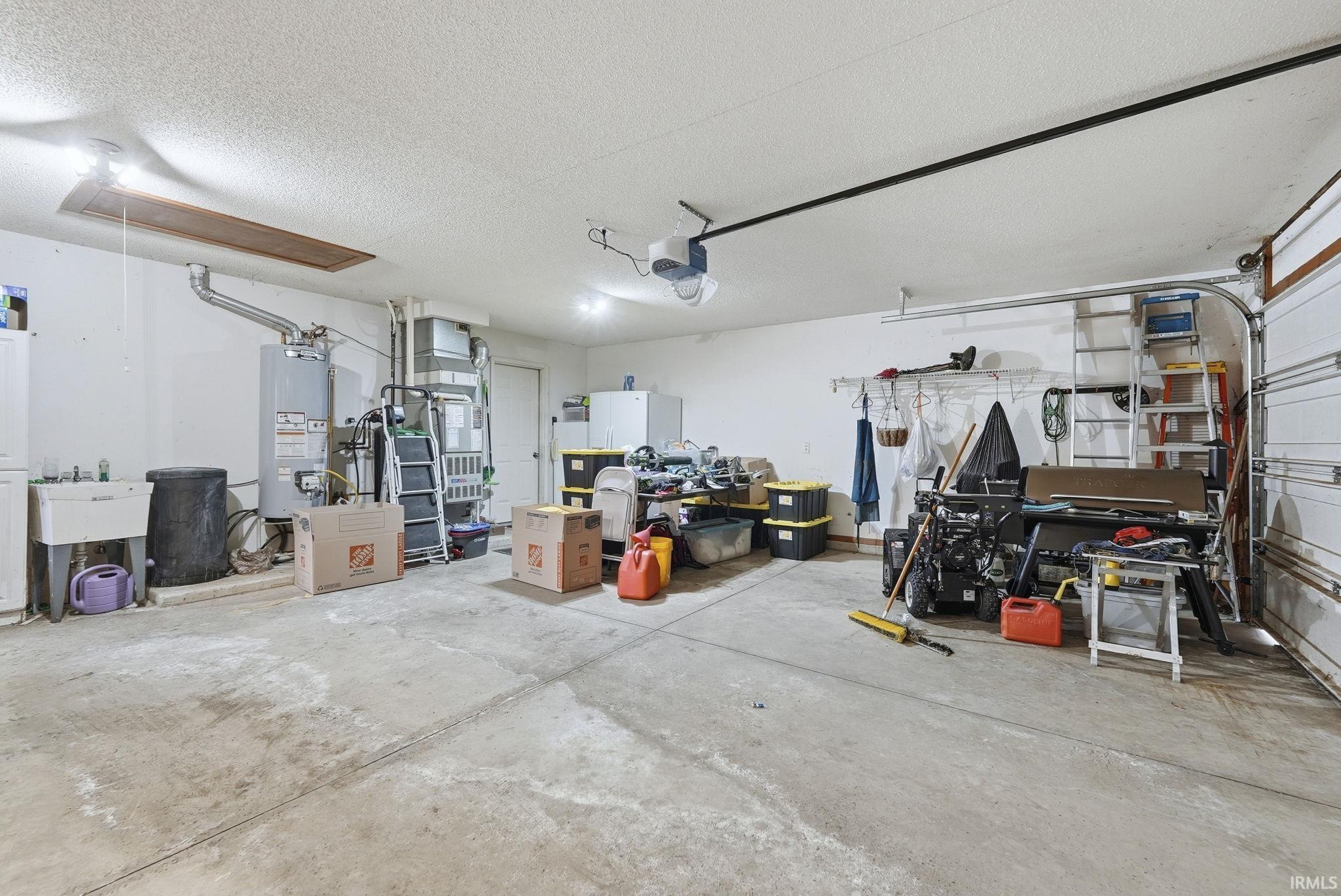 Garage with water heater, heating unit, and a garage door opener