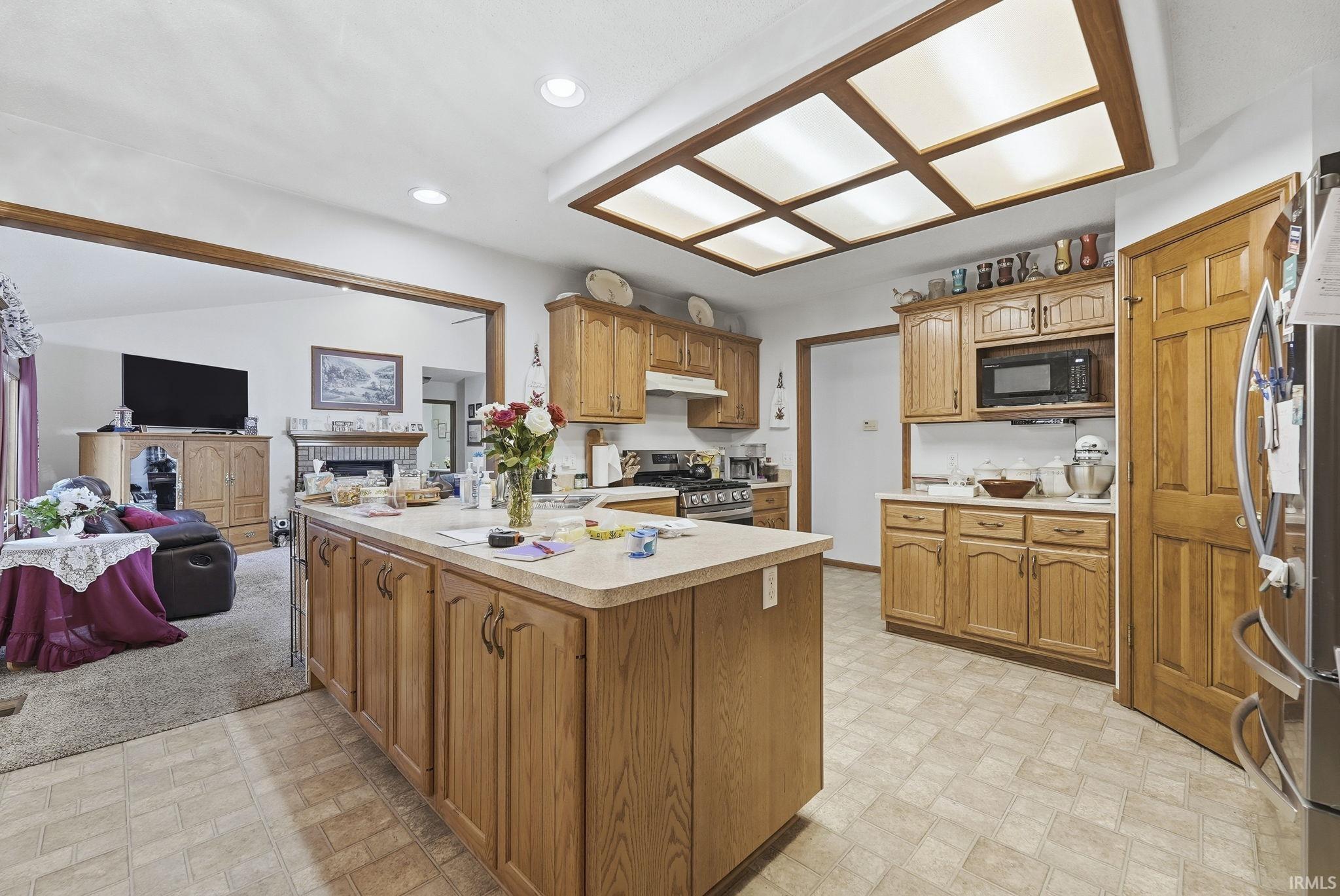 Kitchen with light countertops, open floor plan, wood finish cabinets, a peninsula, and recessed lighting