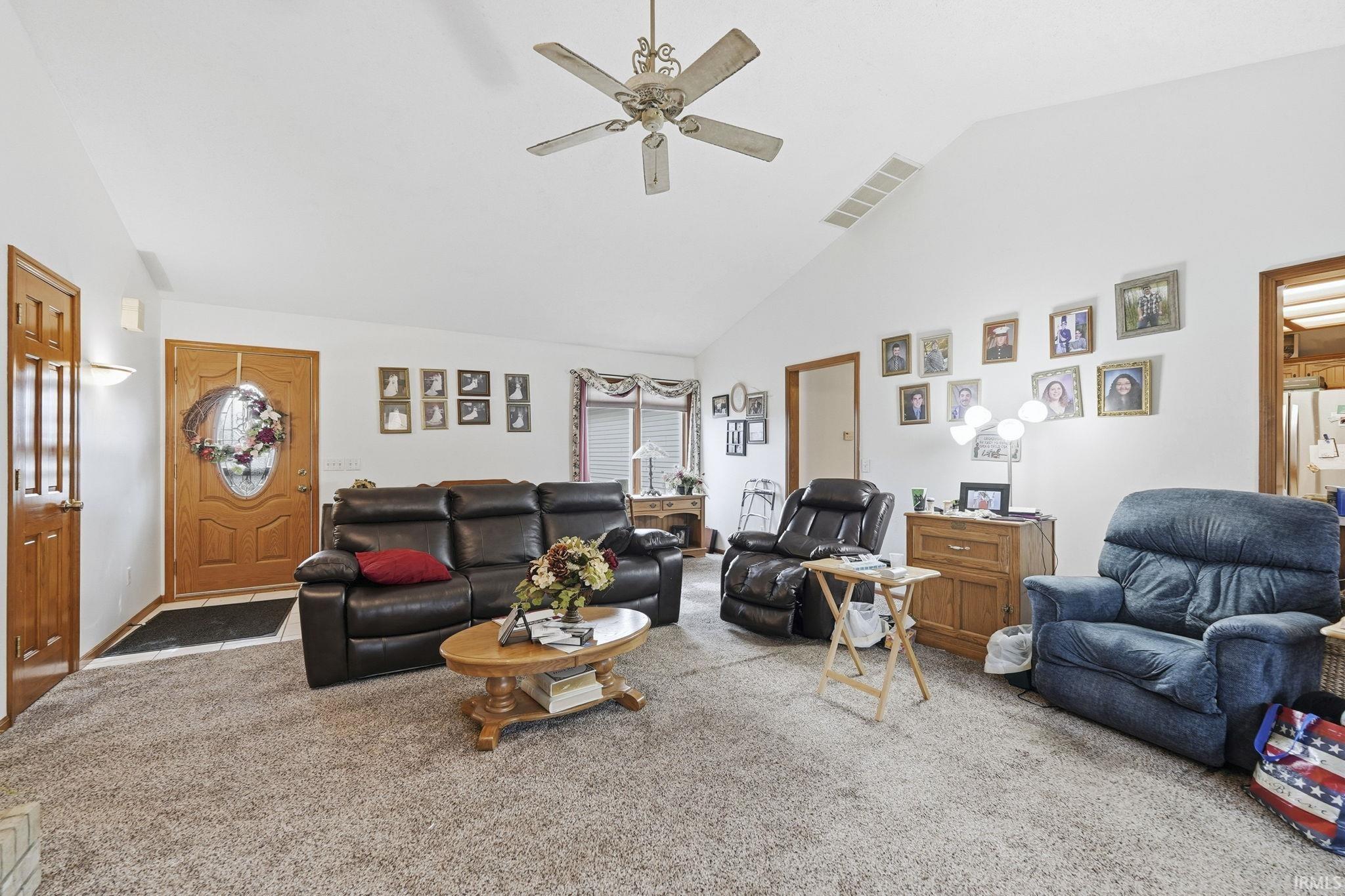 Living area with lofted ceiling, carpet flooring, and a ceiling fan