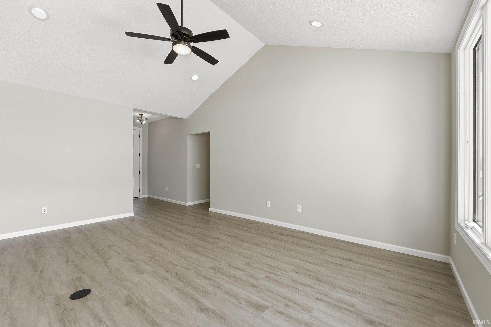 Empty room featuring a ceiling fan, a high ceiling, light wood finished floors, and recessed lighting