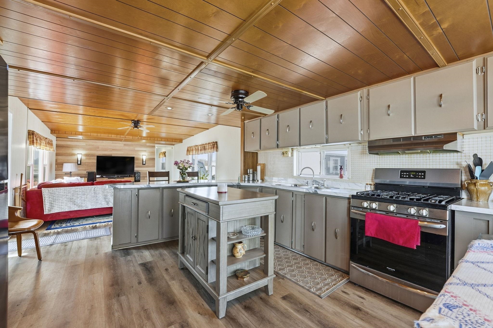 Kitchen with stainless steel range with gas stovetop, wooden ceiling, open floor plan, gray cabinets, and a peninsula