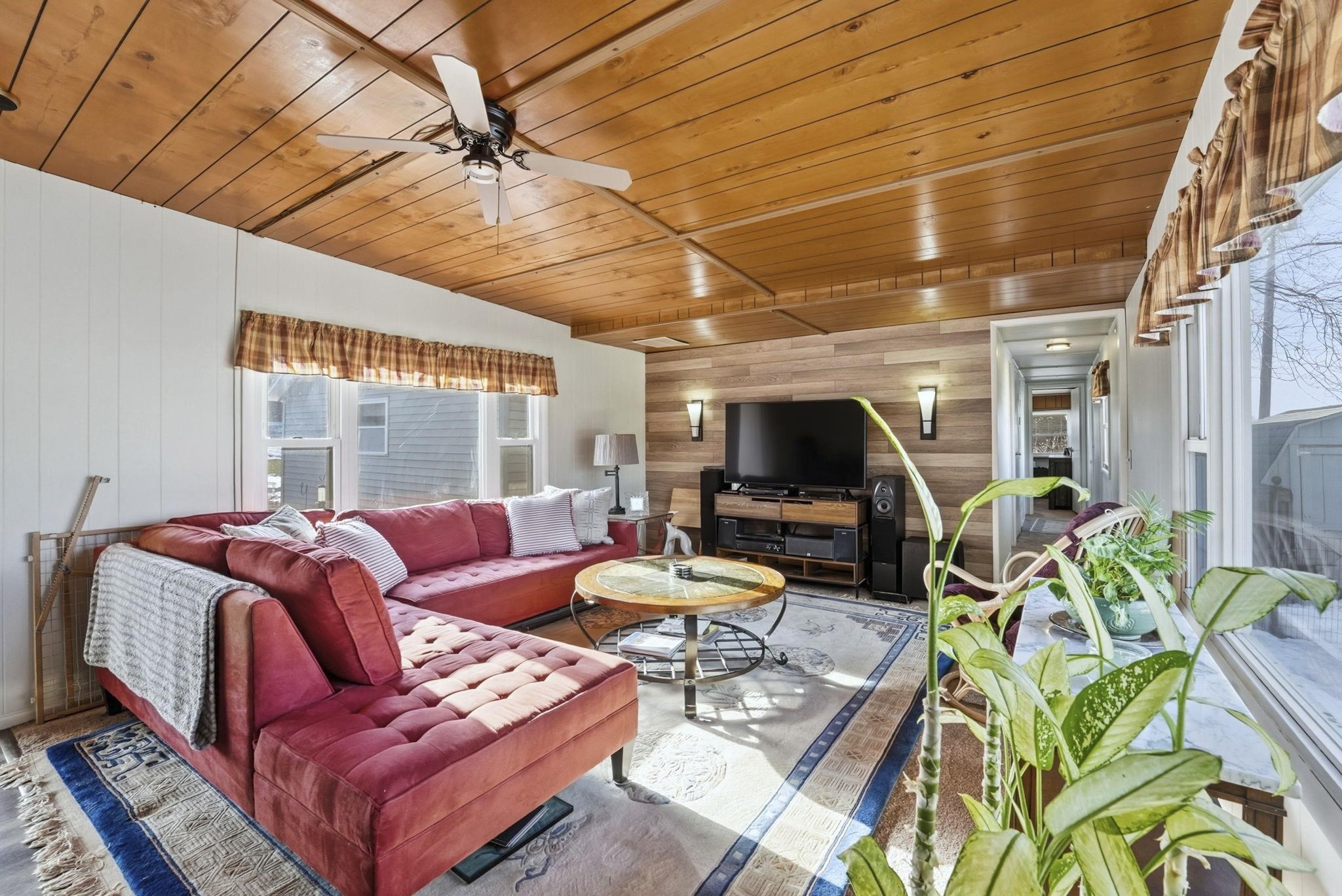 Living area with wood walls, wooden ceiling, and ceiling fan