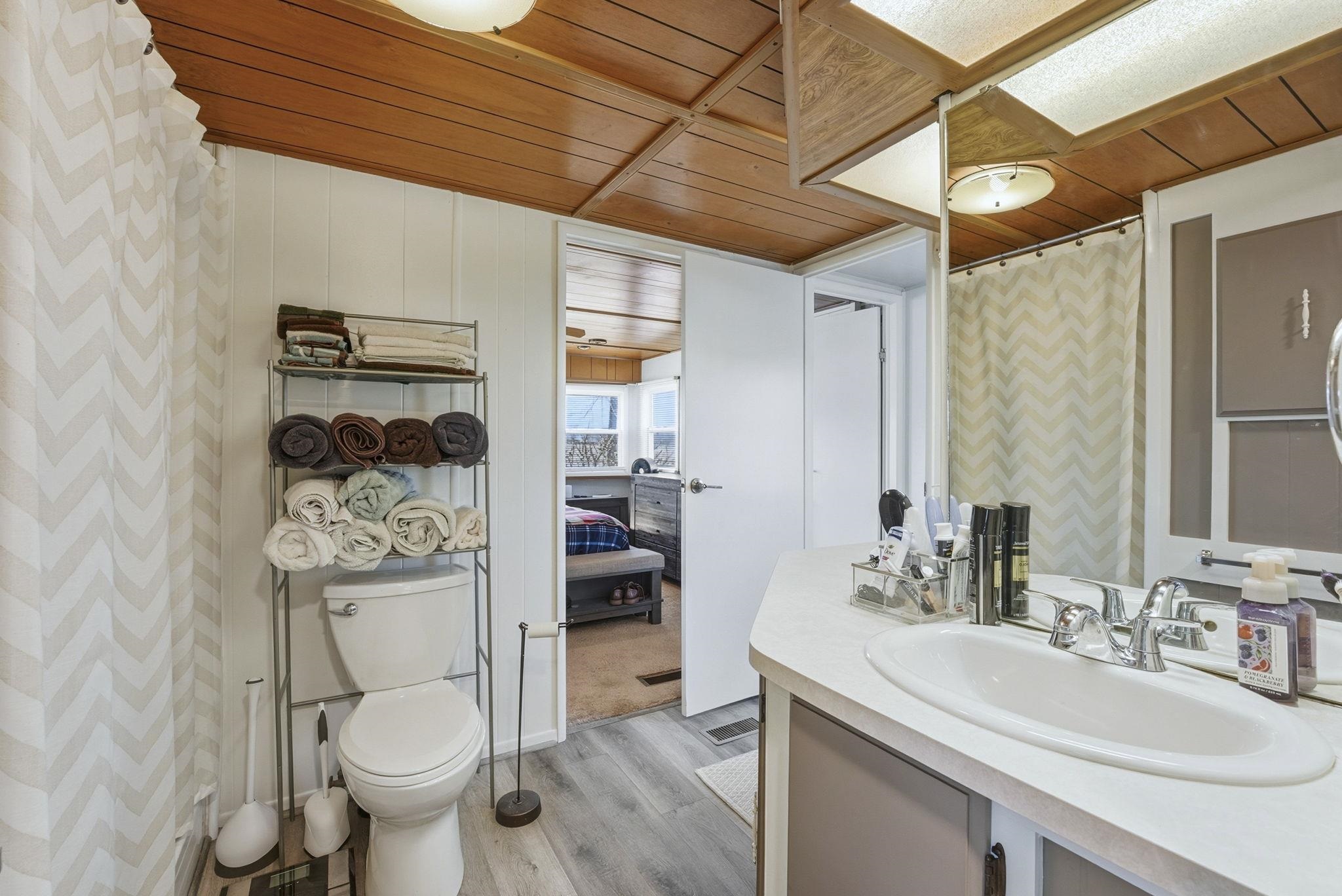 Ensuite bathroom with wooden ceiling, curtained shower, vanity, and light wood-style flooring