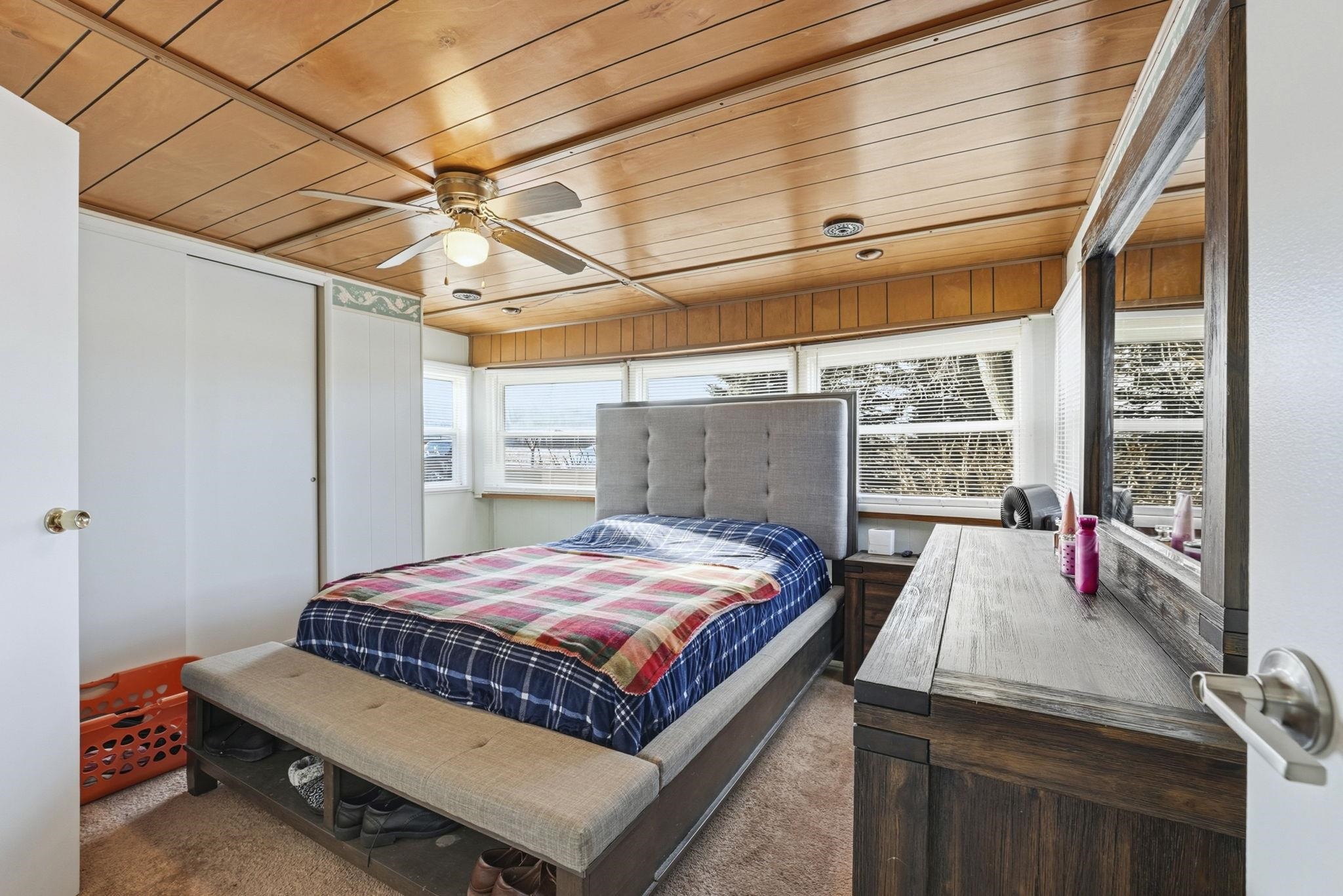 Carpeted bedroom with wood ceiling and ceiling fan