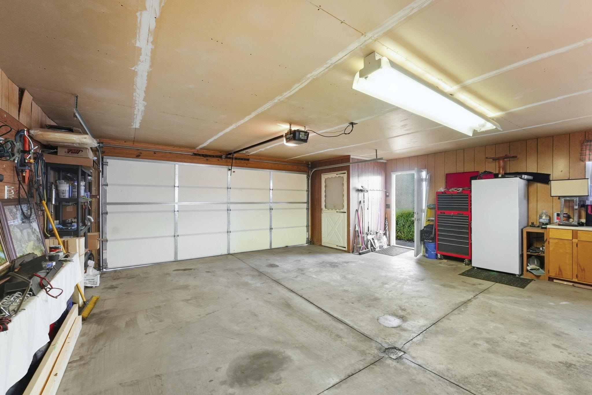 Garage with freestanding refrigerator and a garage door opener