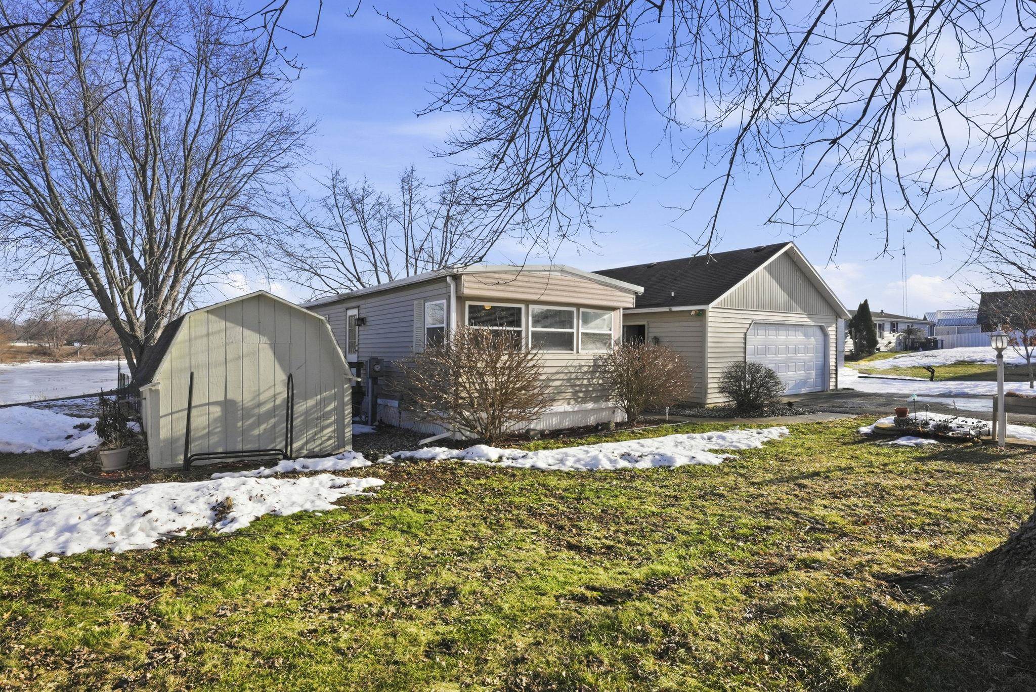 View of front facade with a shed, driveway, an attached garage, and a front yard